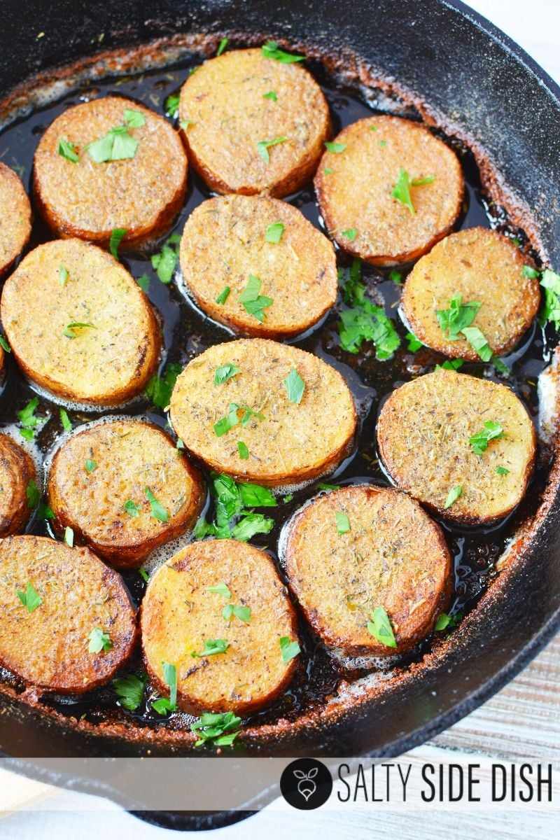 Melting potato recipe sitting in cast iron pan with fresh herbs sprinkled on top