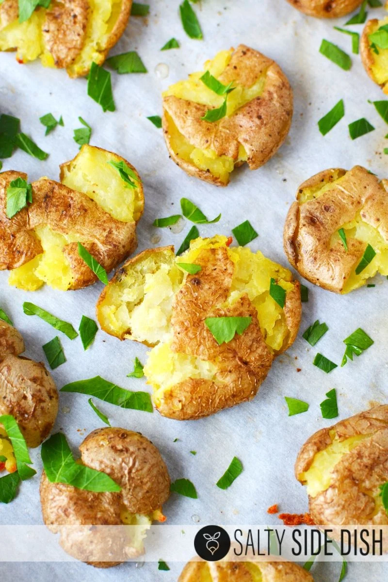 Oven Roasted Smashed mini white potatoes with fresh parsley on a baking sheet