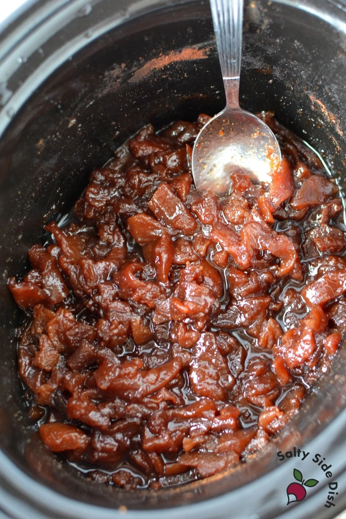 apples cooked in a slow cooker being stirred