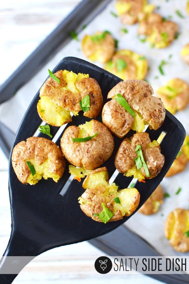 Fully roasted mini potatoes on a black spatula, ready to serve