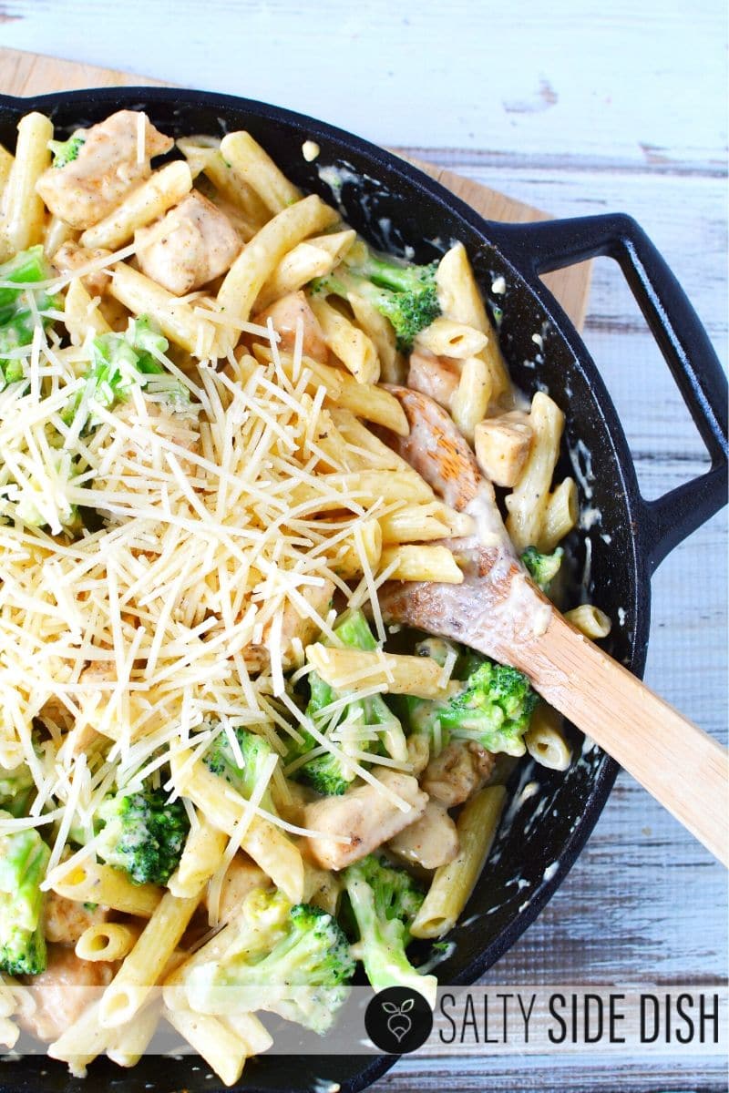 Finished Cajun Chicken pasta with parmesan cheese and a spoon in a cast iron pan