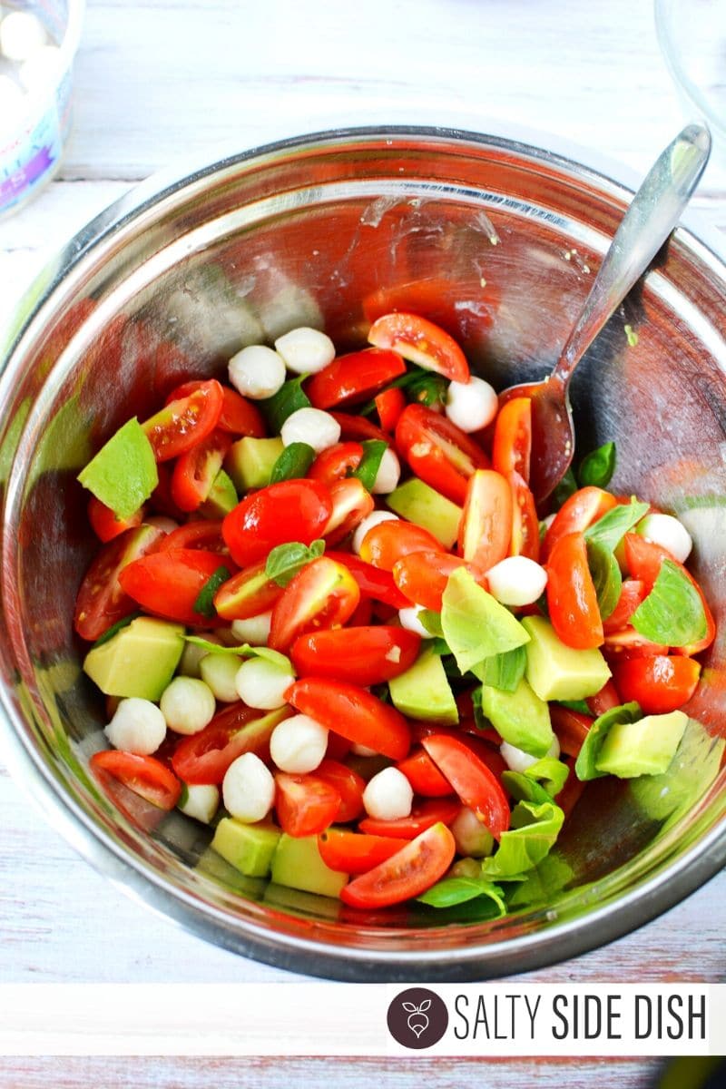quartered tomatoes, mozzarella pearls, and avocado in a bowl with lemon
