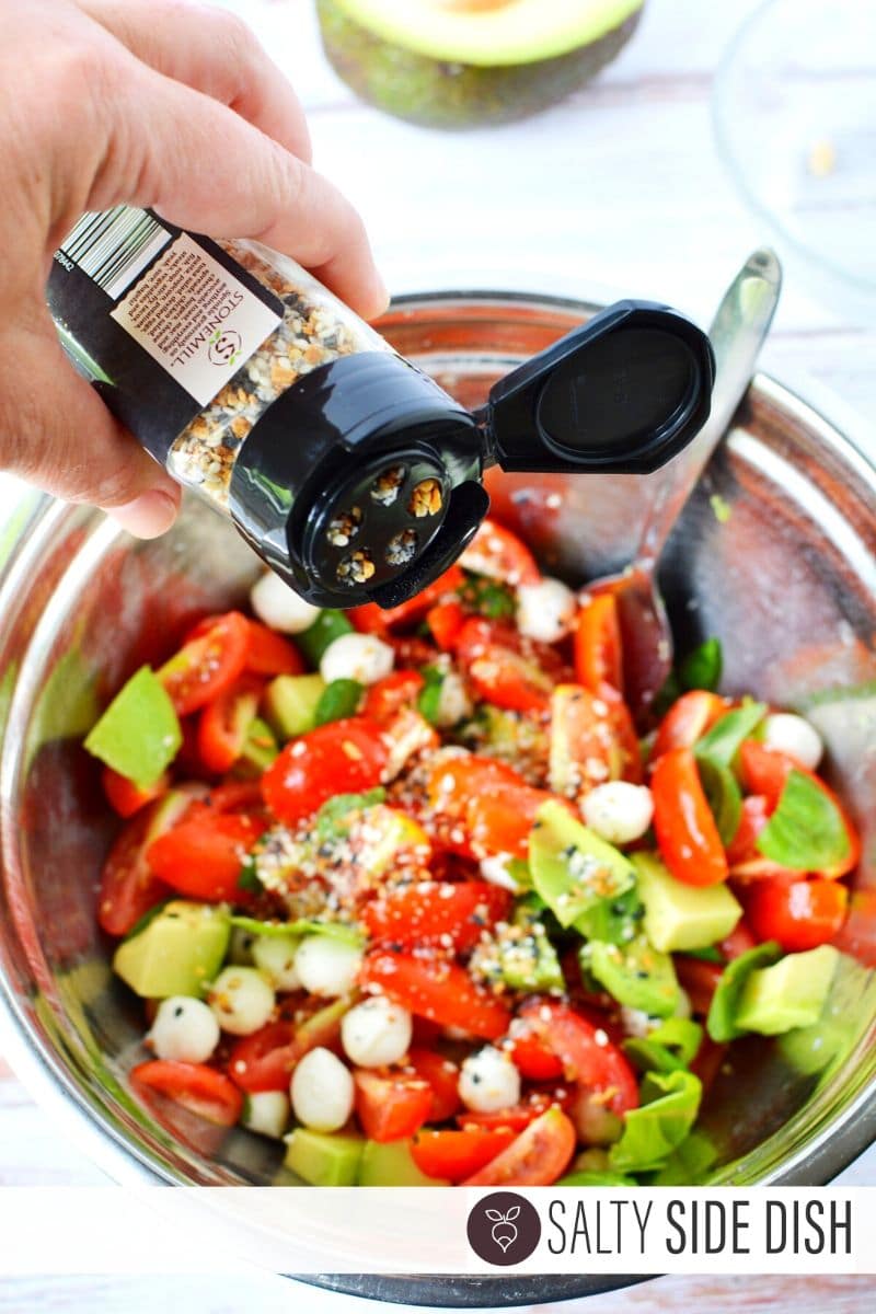 Everything Bagel Seasoning being added to caprese salad