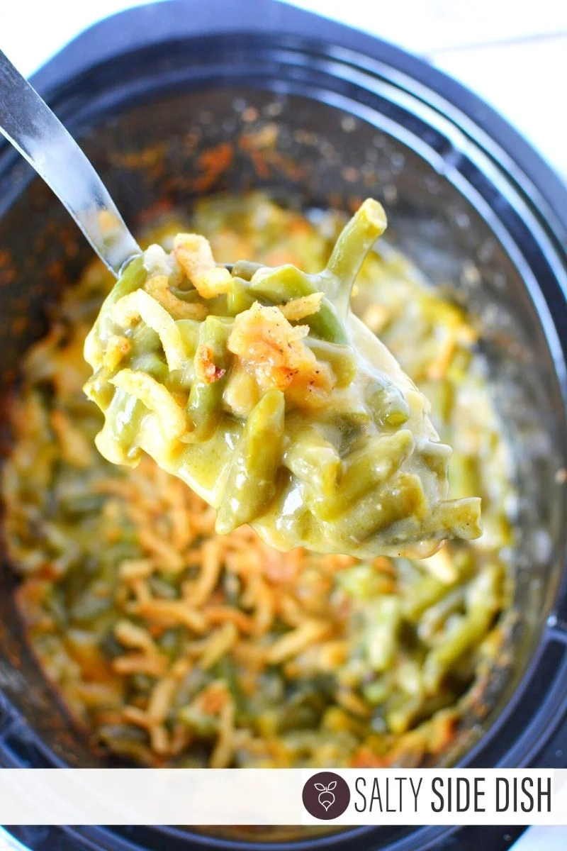 slow cooker green bean casserole being scooped out with a spoon