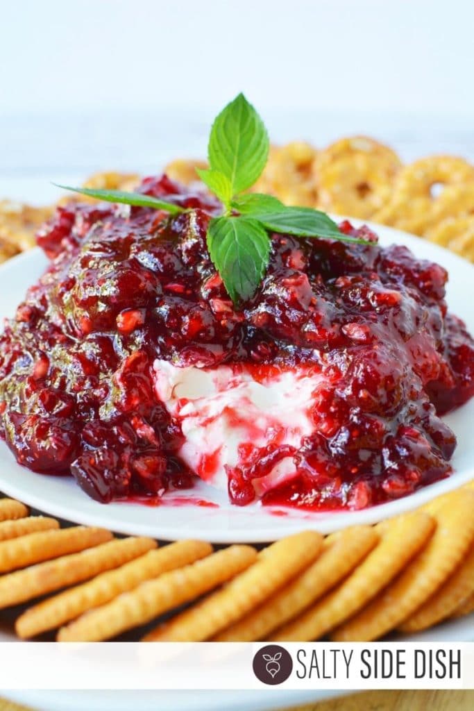 cranberry cream cheese dip with chunk out of it and mint on top