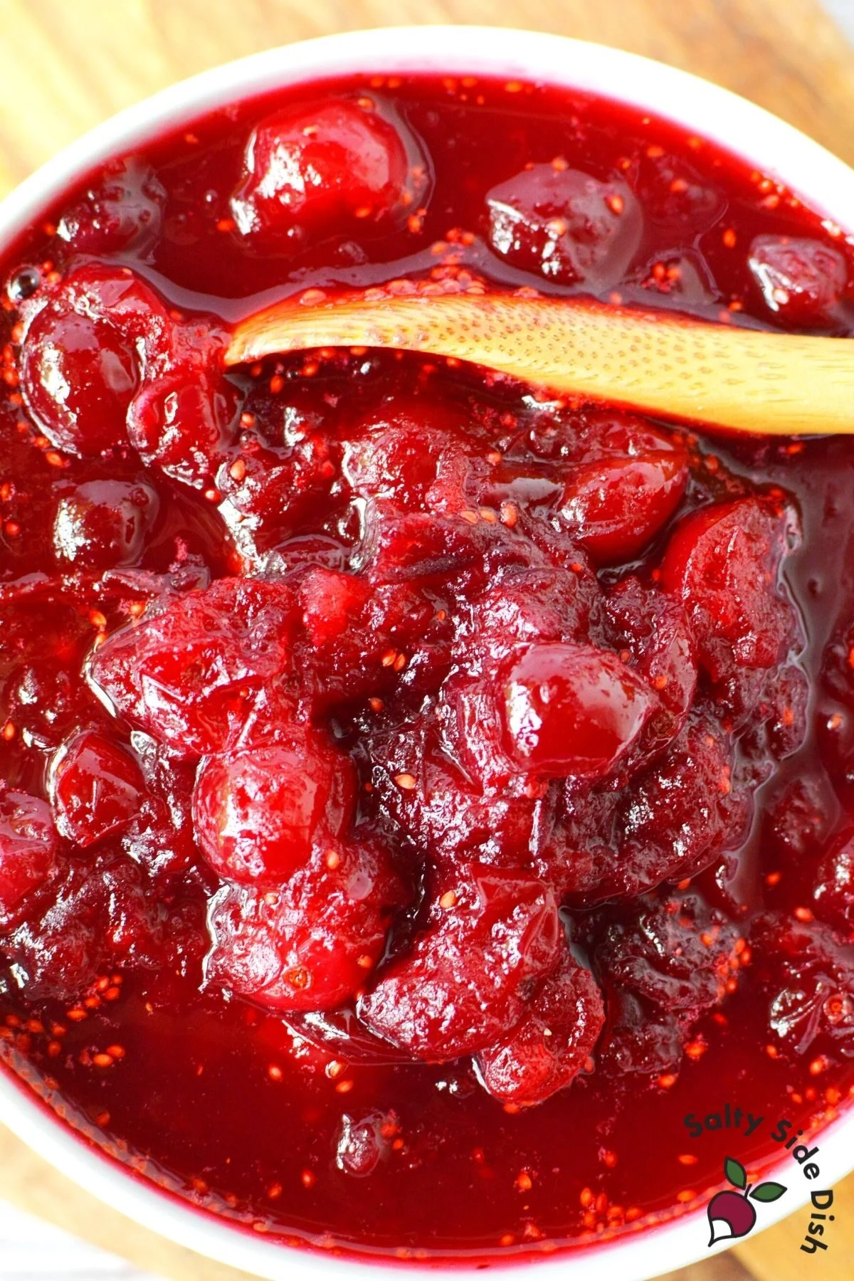 cranberry sauce in a white bowl with a wooden spoon