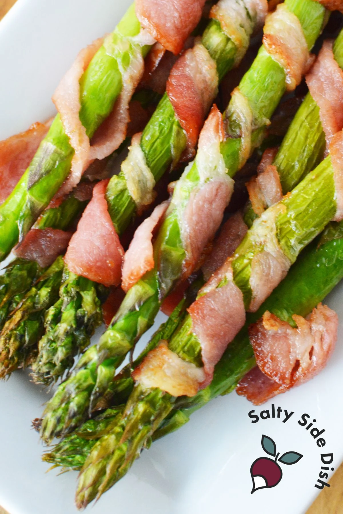 fully wrapped bacon wrapped asparagus piled high on a plate.