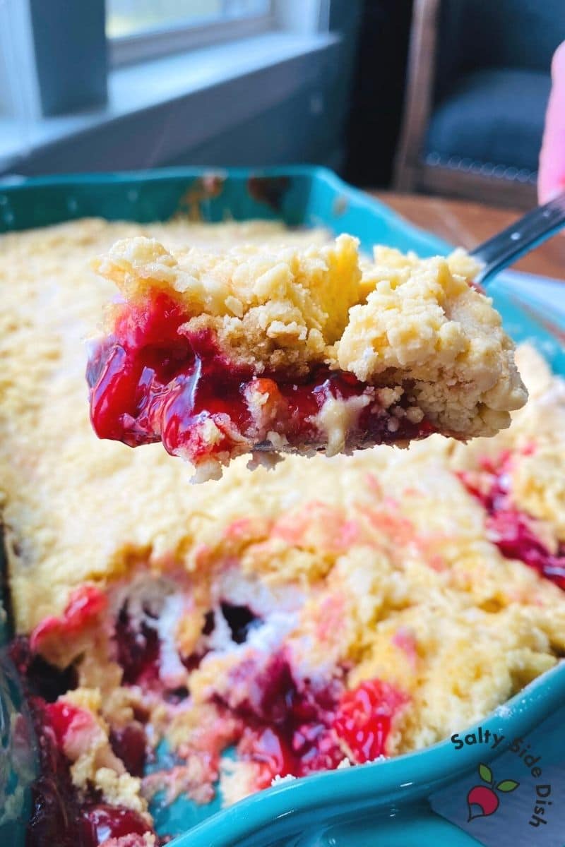Cherry Cream Cheese Dump cake with chessman cookies being scooped out of casserole dish and ready to serve