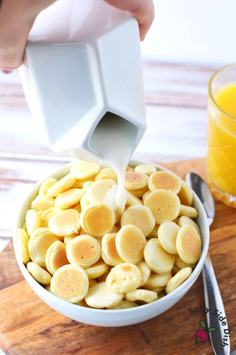 pouring milk over mini pancakes