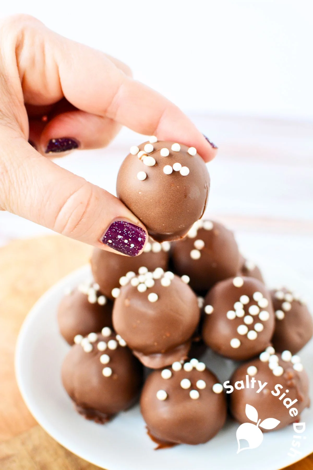 holding a chocolate covered cake ball.
