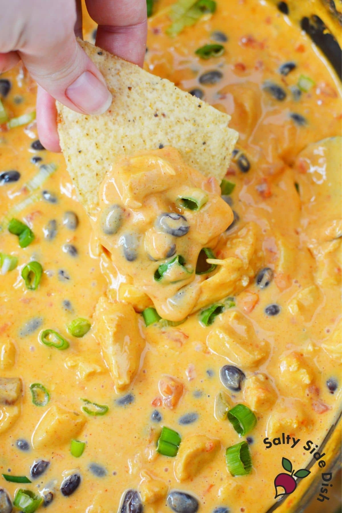 Velveeta cheese dip made in a slow cooker with tortilla dipping out a generous scoop to eat