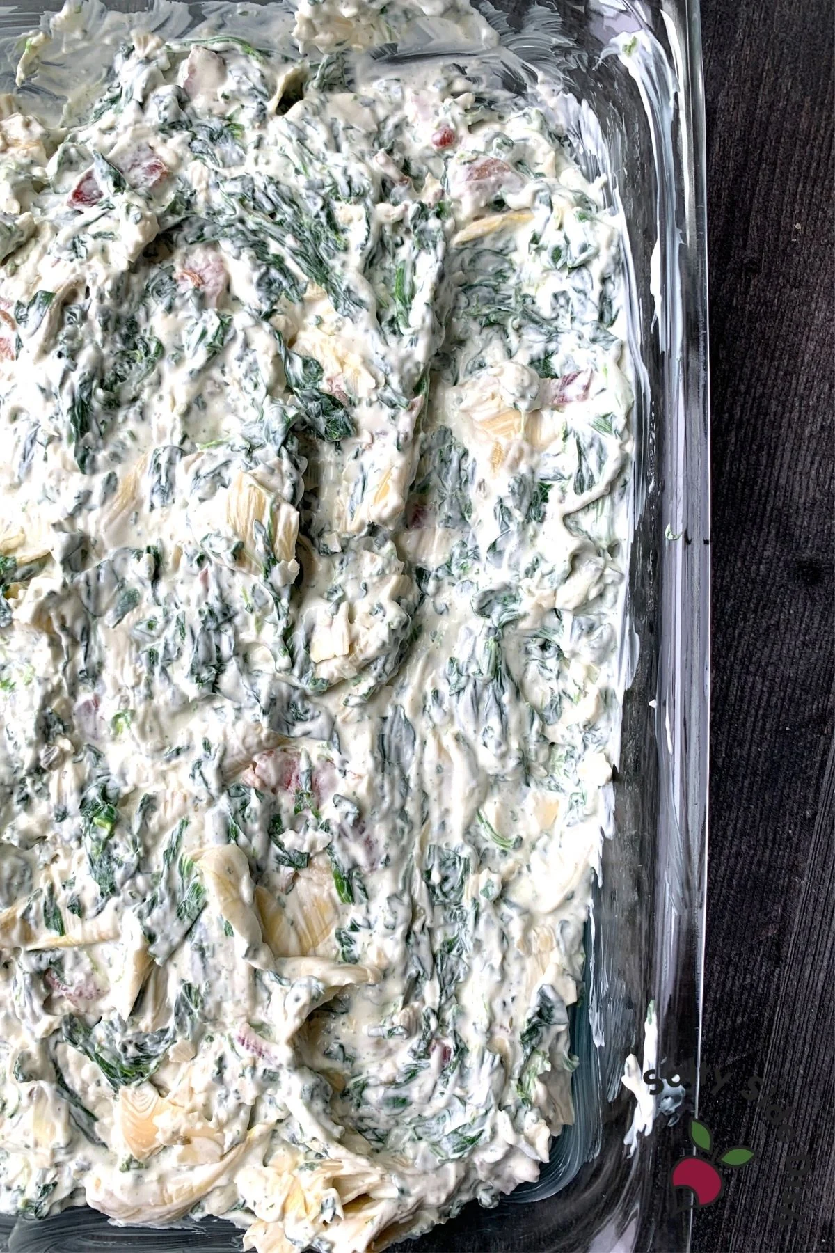 smoothed out cream cheese and spinach dip in a casserole dish ready to bake