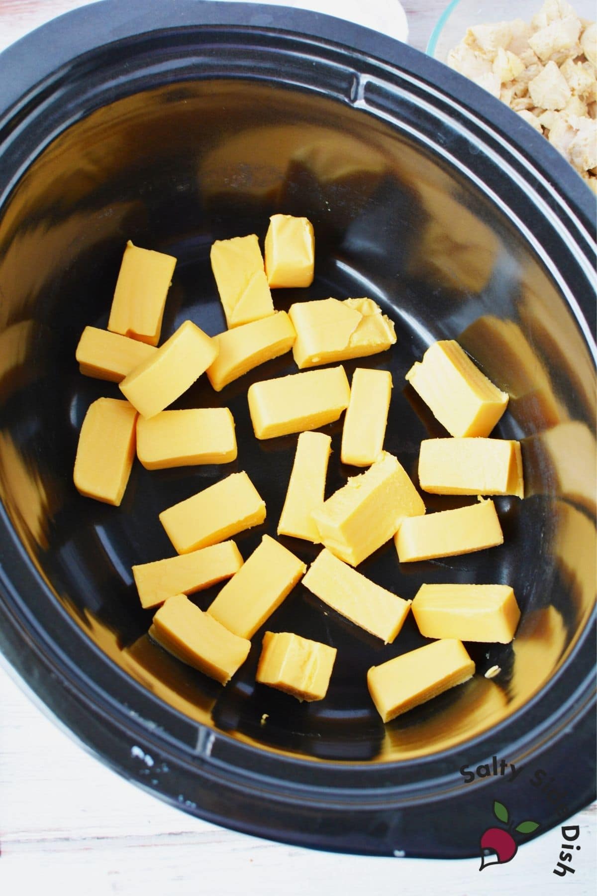 cut up pieces of Velveeta cheese in the bottom of a slow cooker