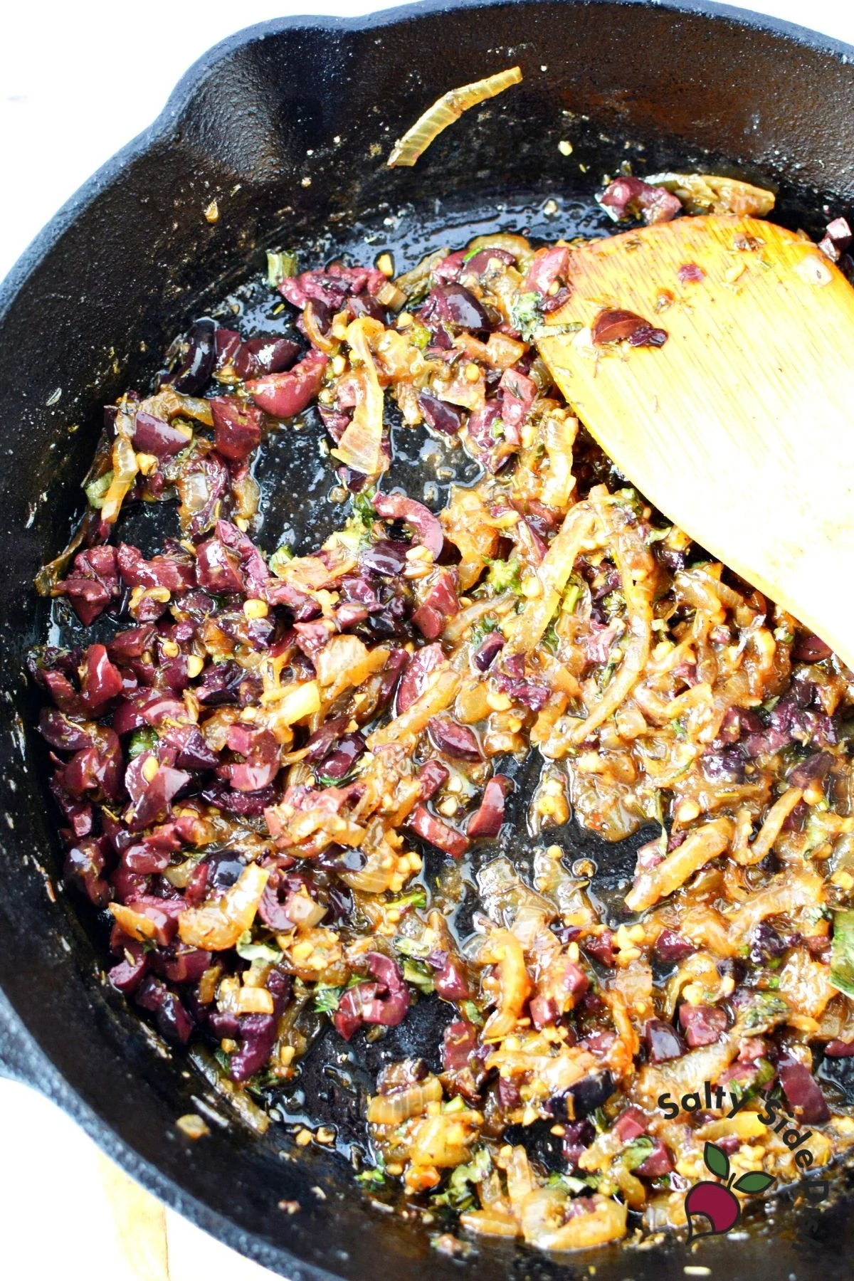 summer squash medly with onions, olives and fresh herbs in a cast iron pan