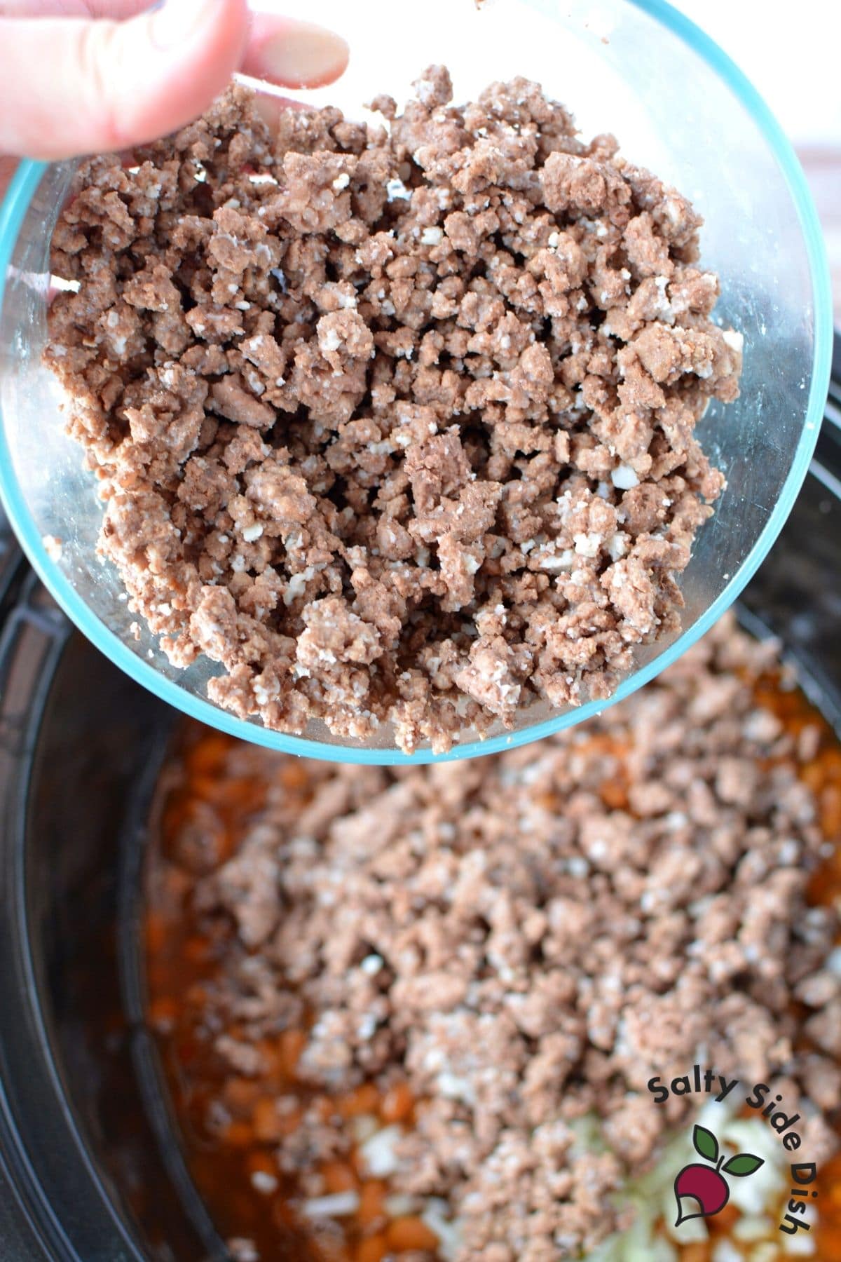 beef being poured into slow cooker