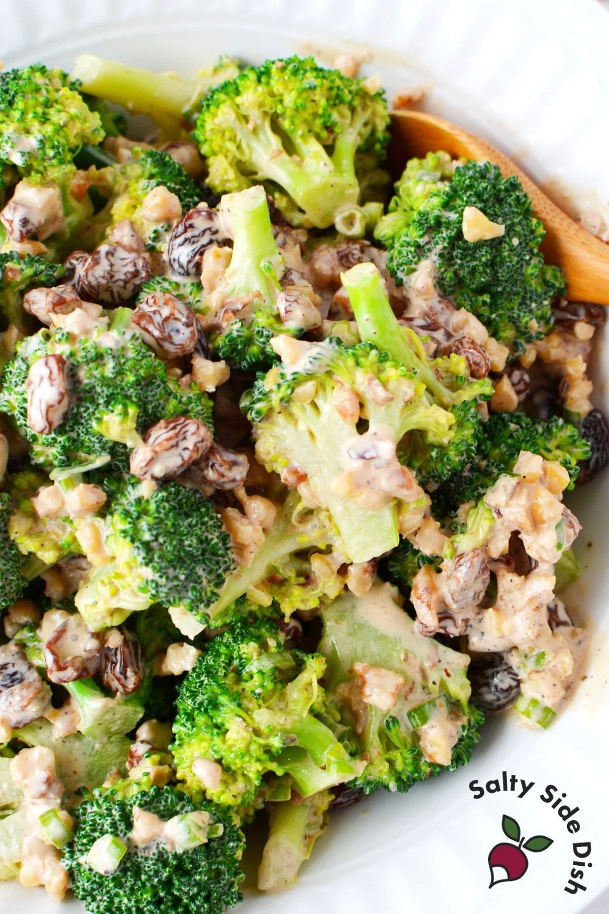 raisin broccoli salad recipe with wooden spoon sitting in a bowl