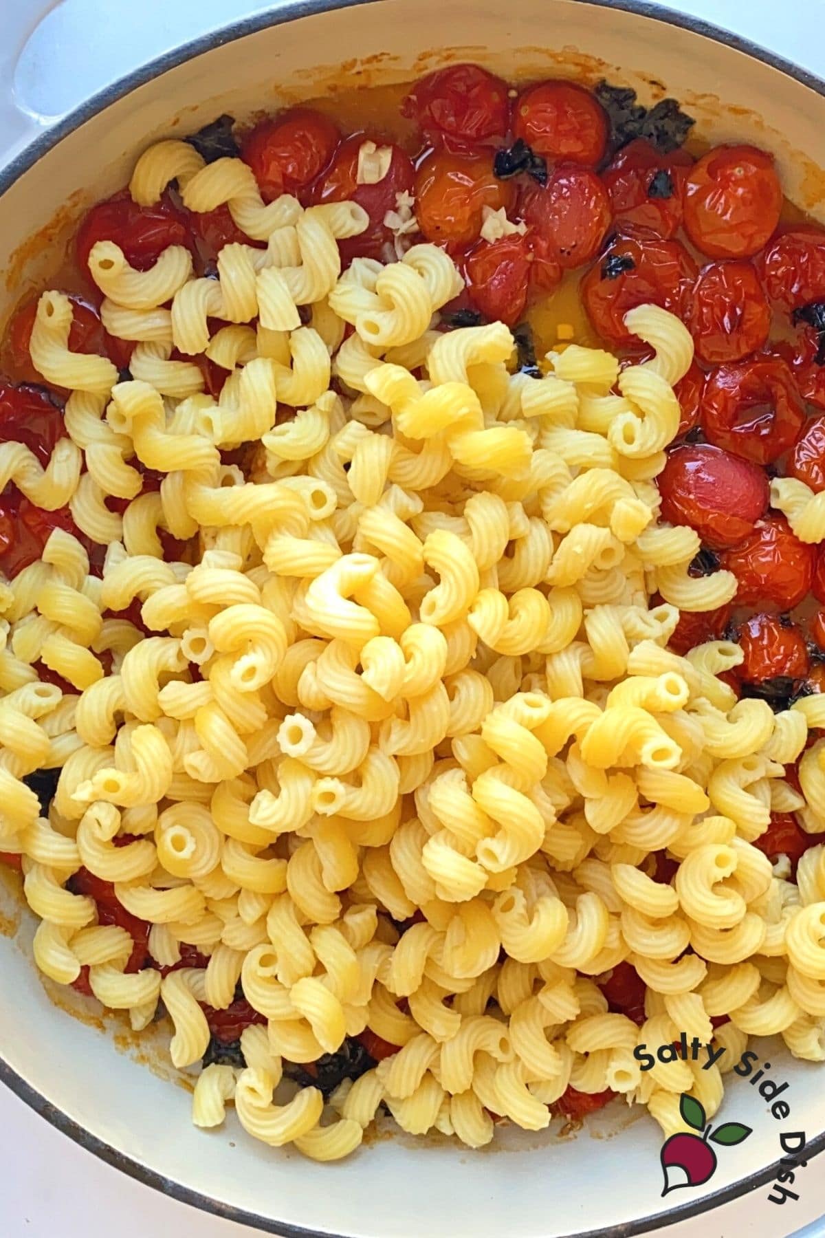 half pasta into dish with cooked tomatoes
