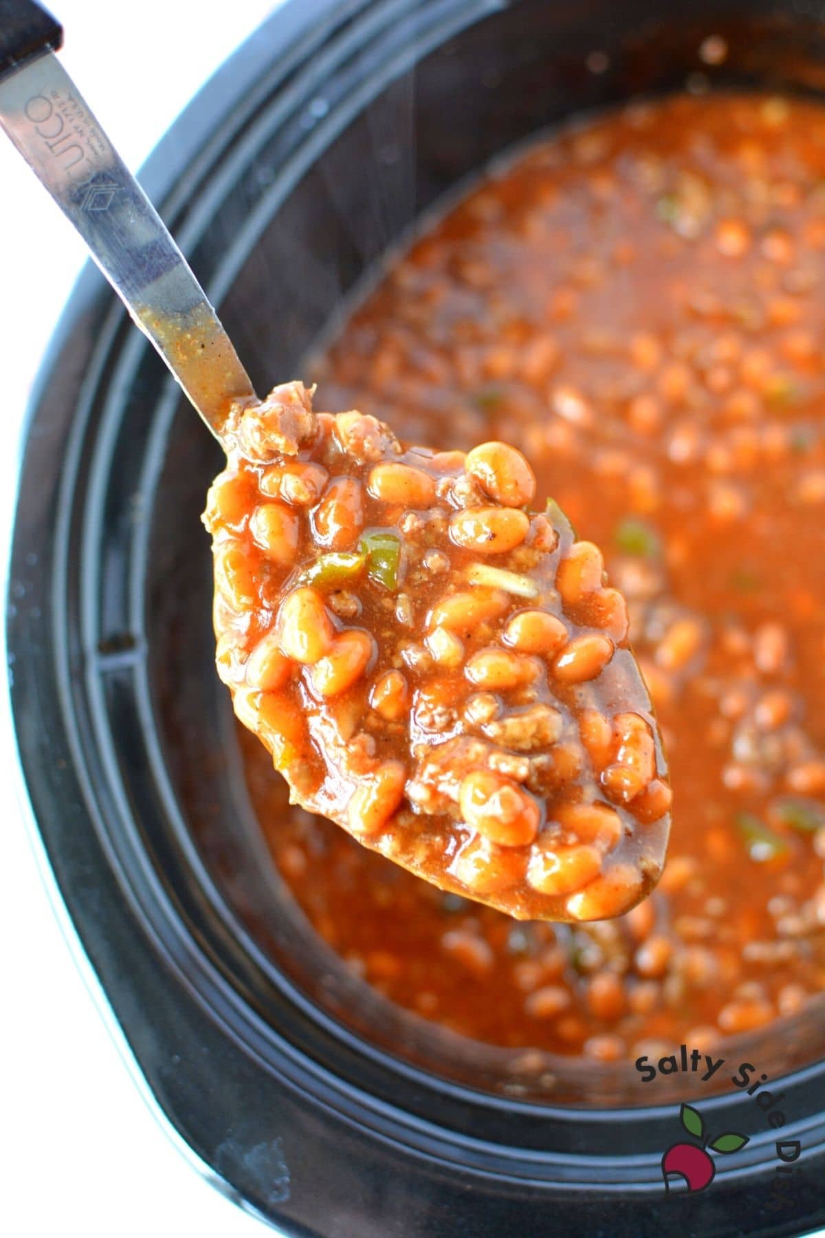 slow cooked baked beans being scooped out of dish
