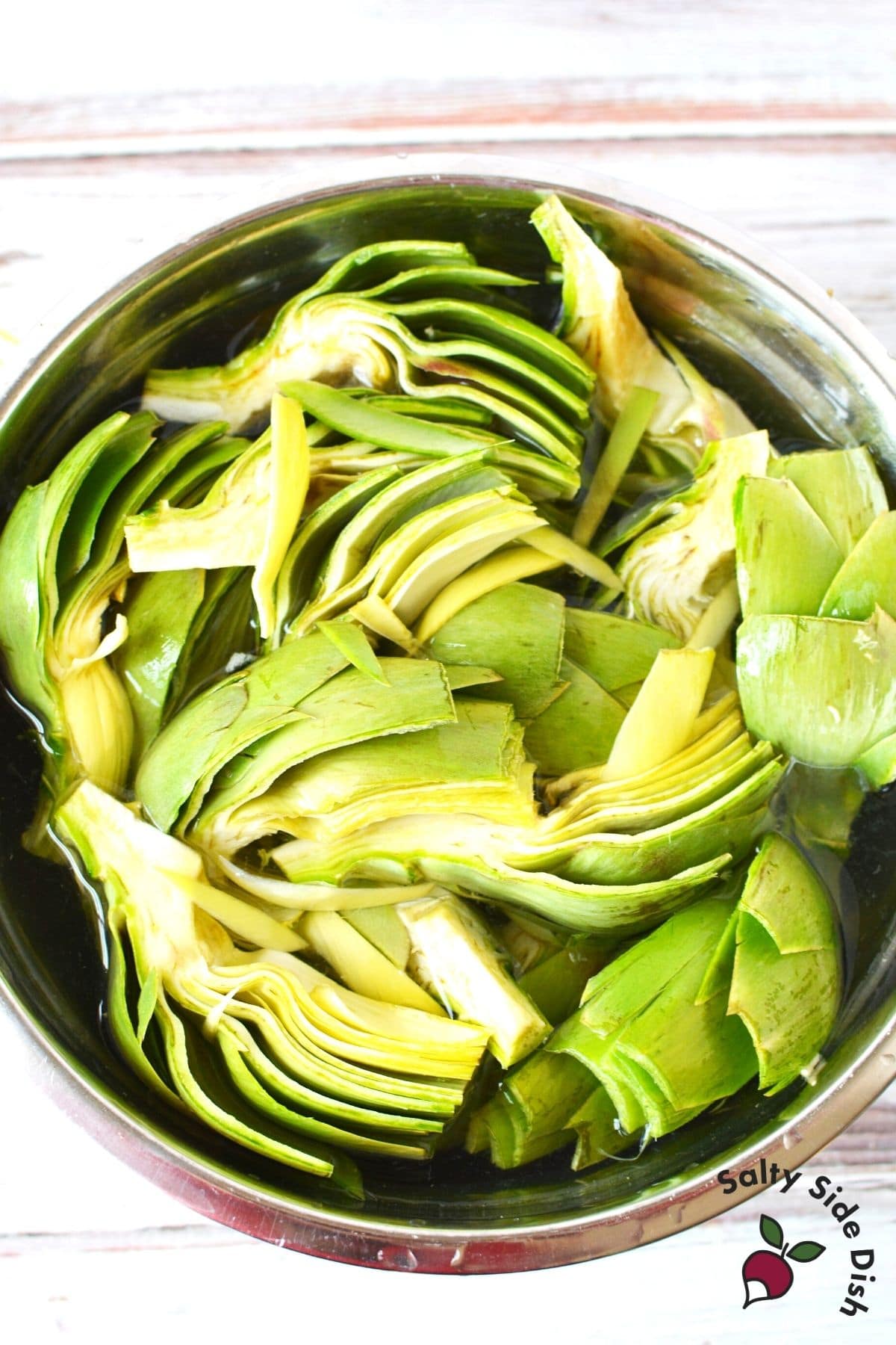 cut artichokes sitting in bowl of lemon water to prevent browning