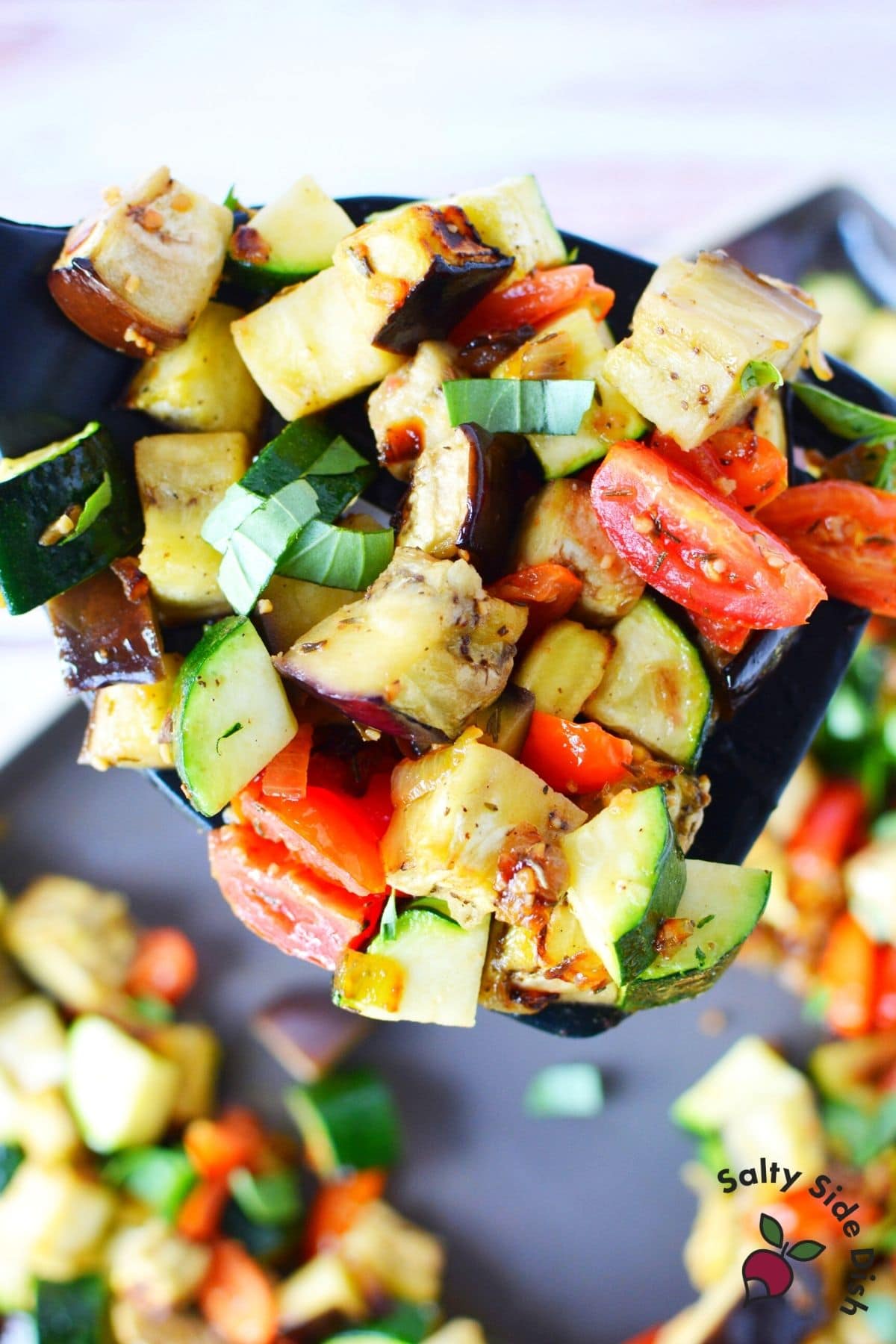 baked sheet pan zucchini eggplant and tomatoes on a spatula ready to serve
