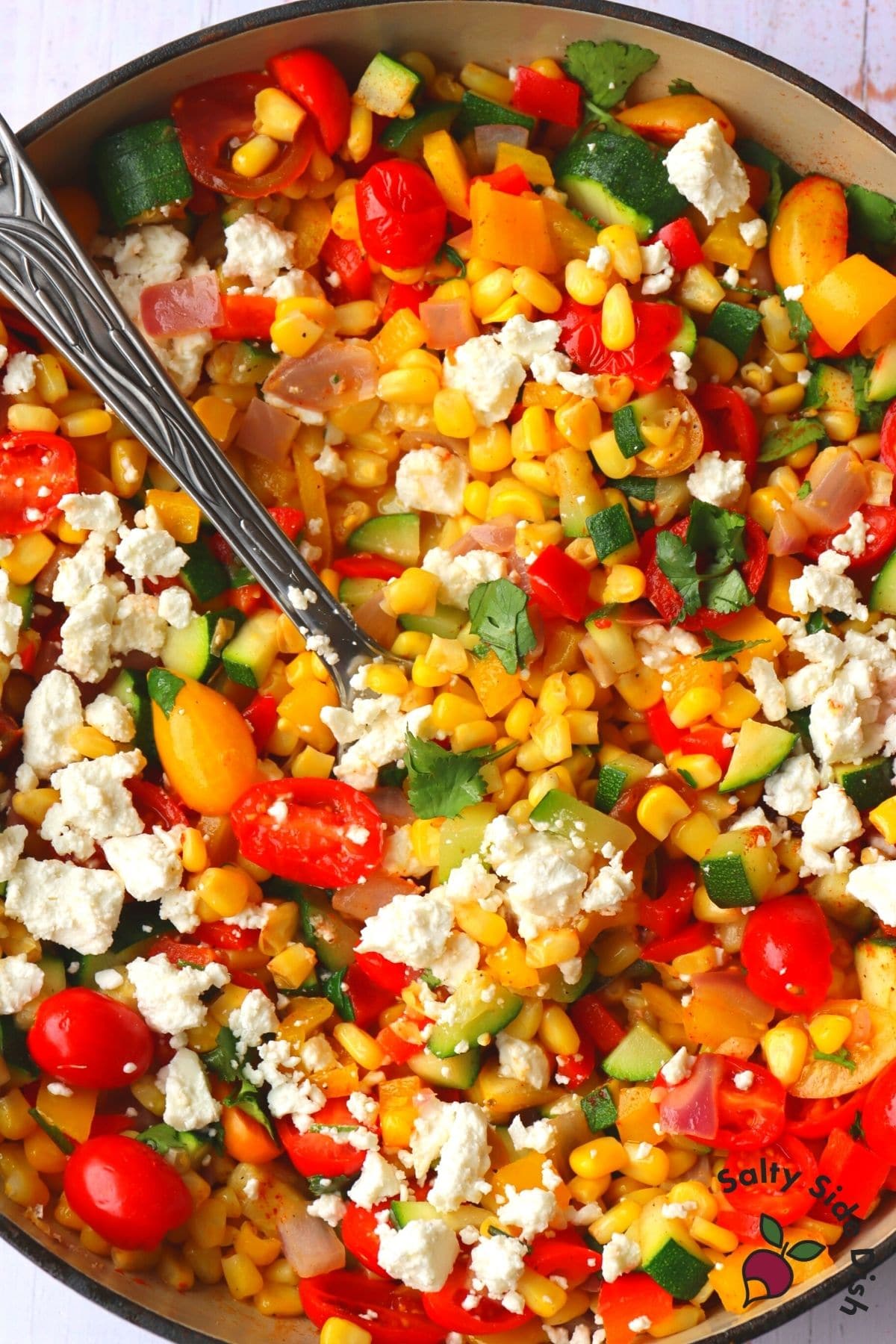 corn succotash in a skillet with a spoon