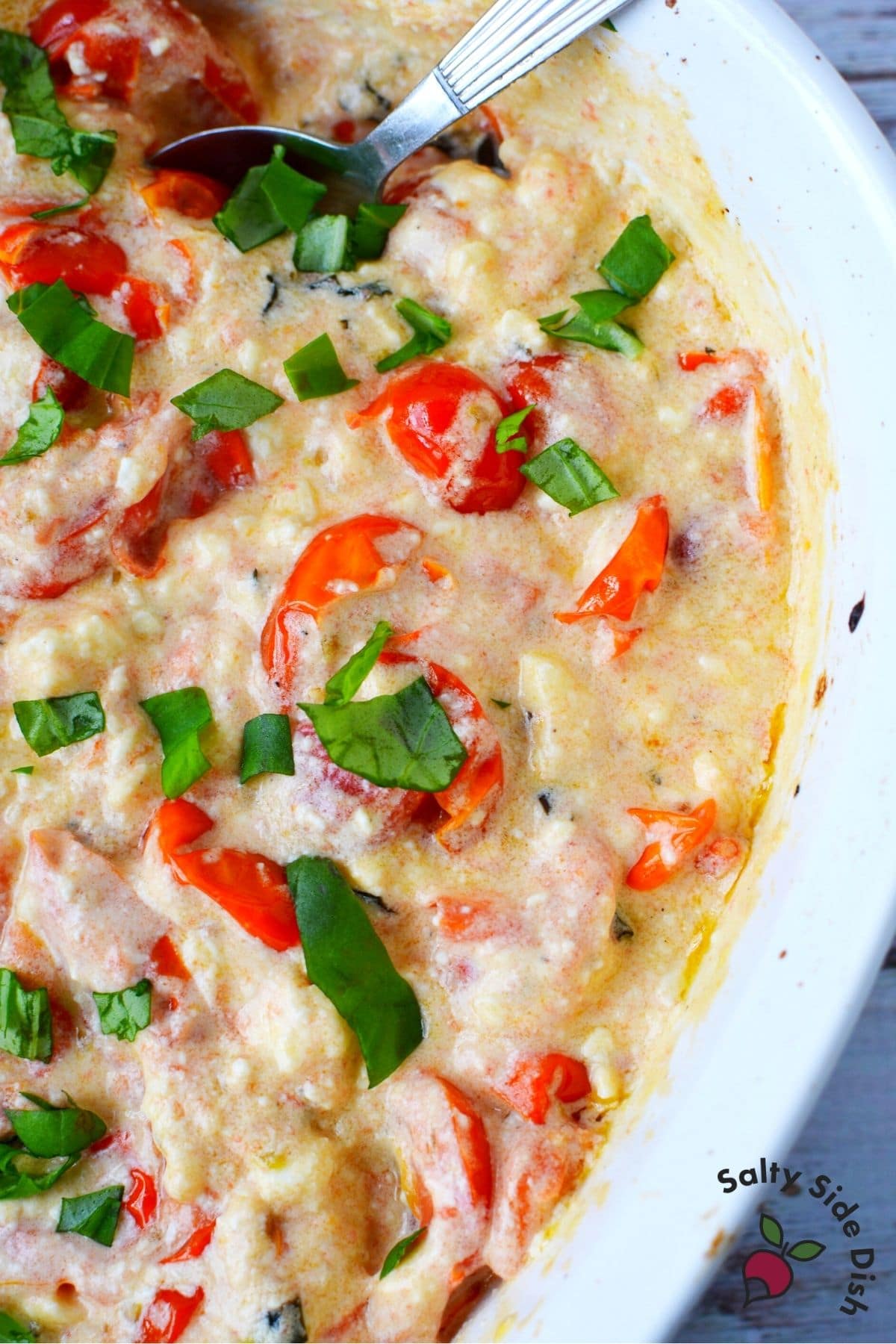 cheese feta dip with basil leaves in a white dish with spoon