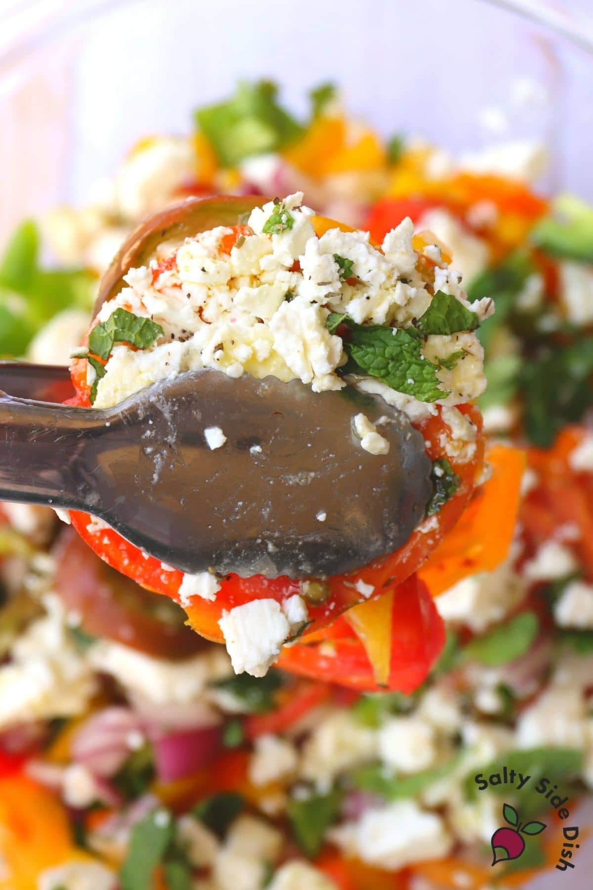 tongs holding Greek tomato salad