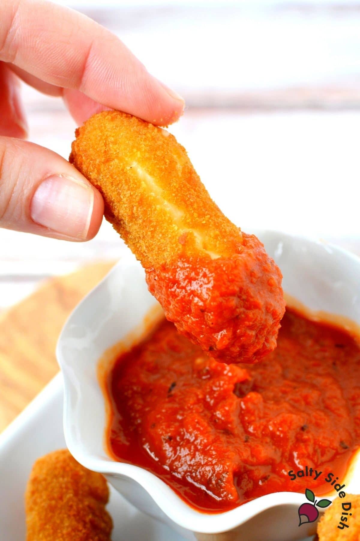 dipping ooey gooey mozzarella stick into marinara sauce