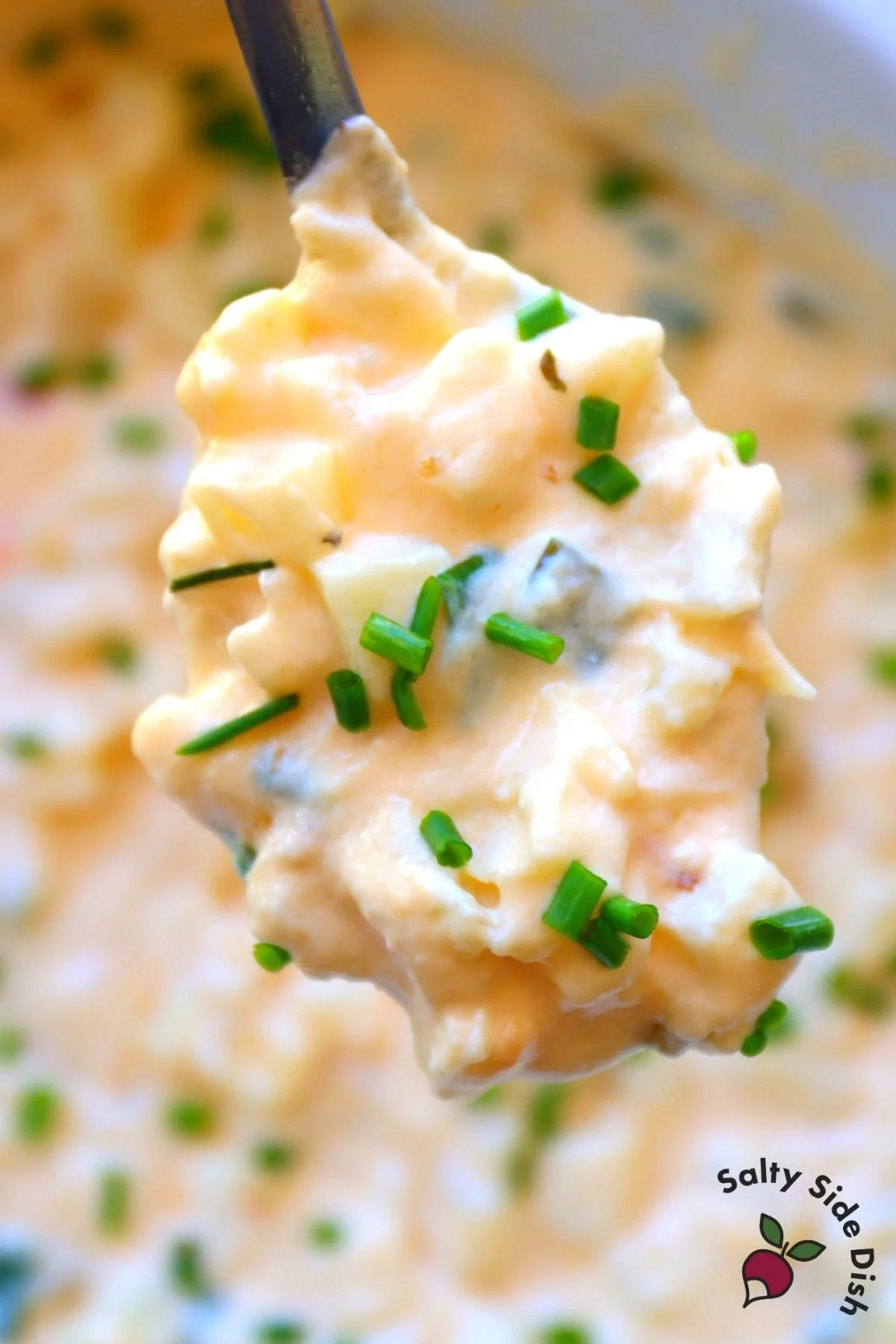 cheesy gouda potatoes on a spoon with chives