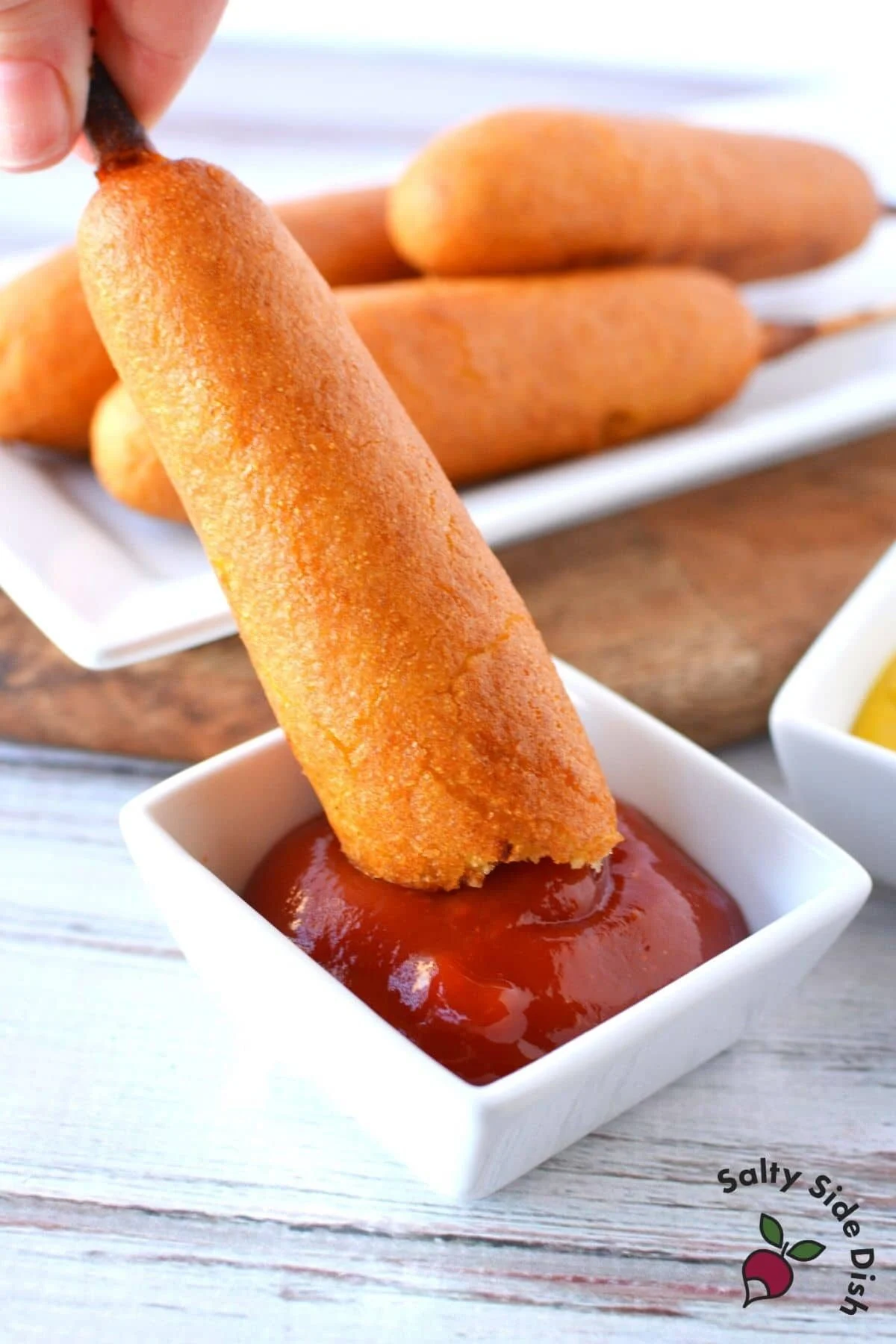 corn dogs being dipped into ketchup