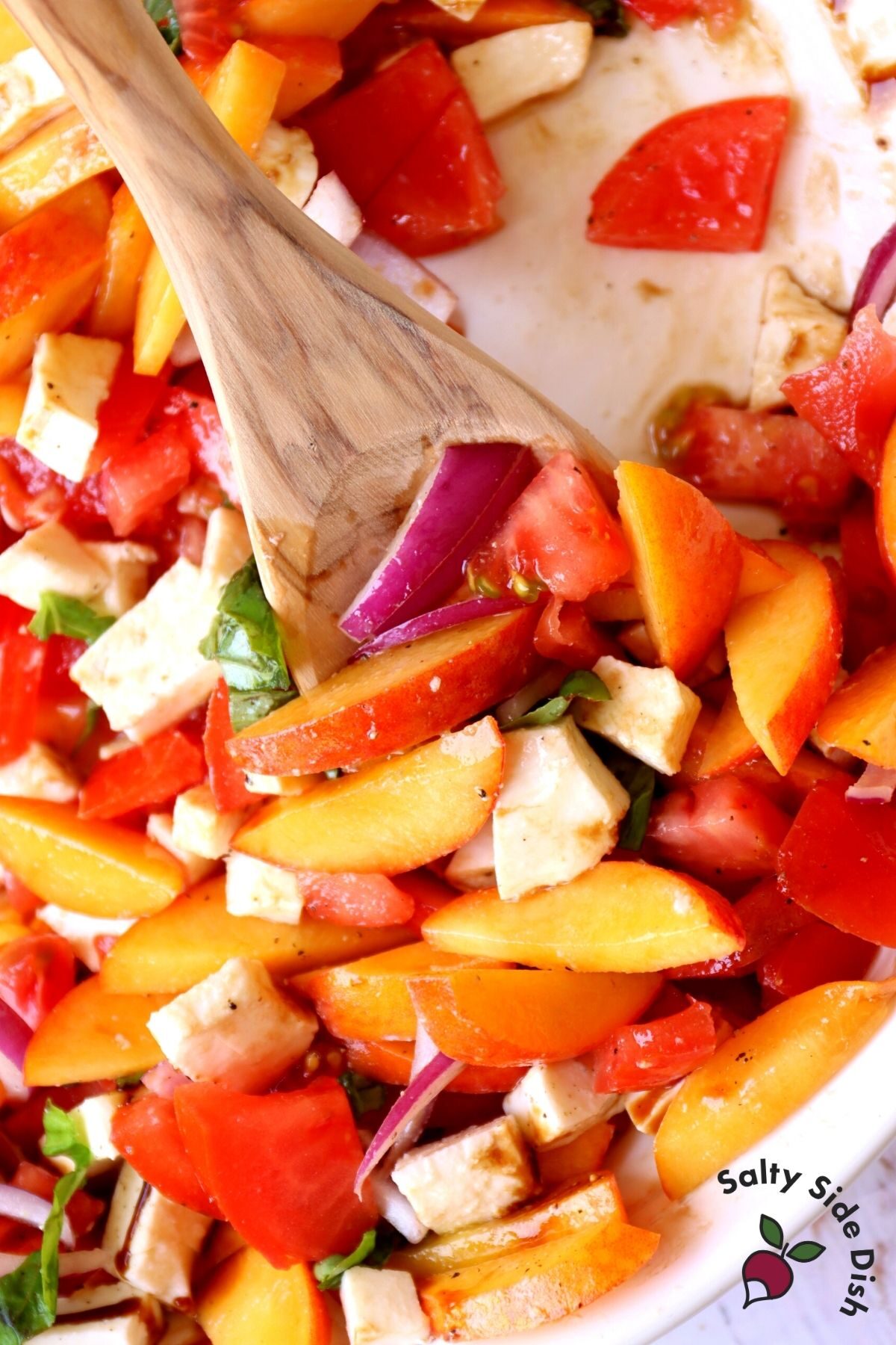 ripe summer peach salad in a bowl being stirred