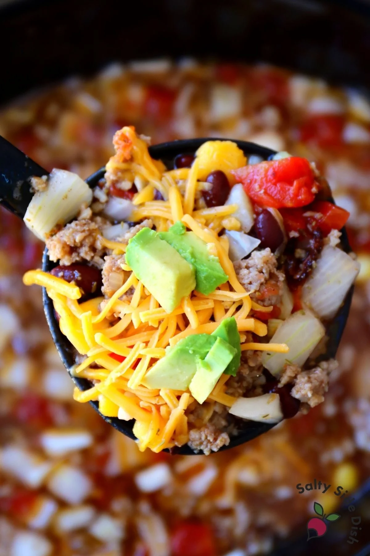 adding avocado and cheese to sausage and black bean soup