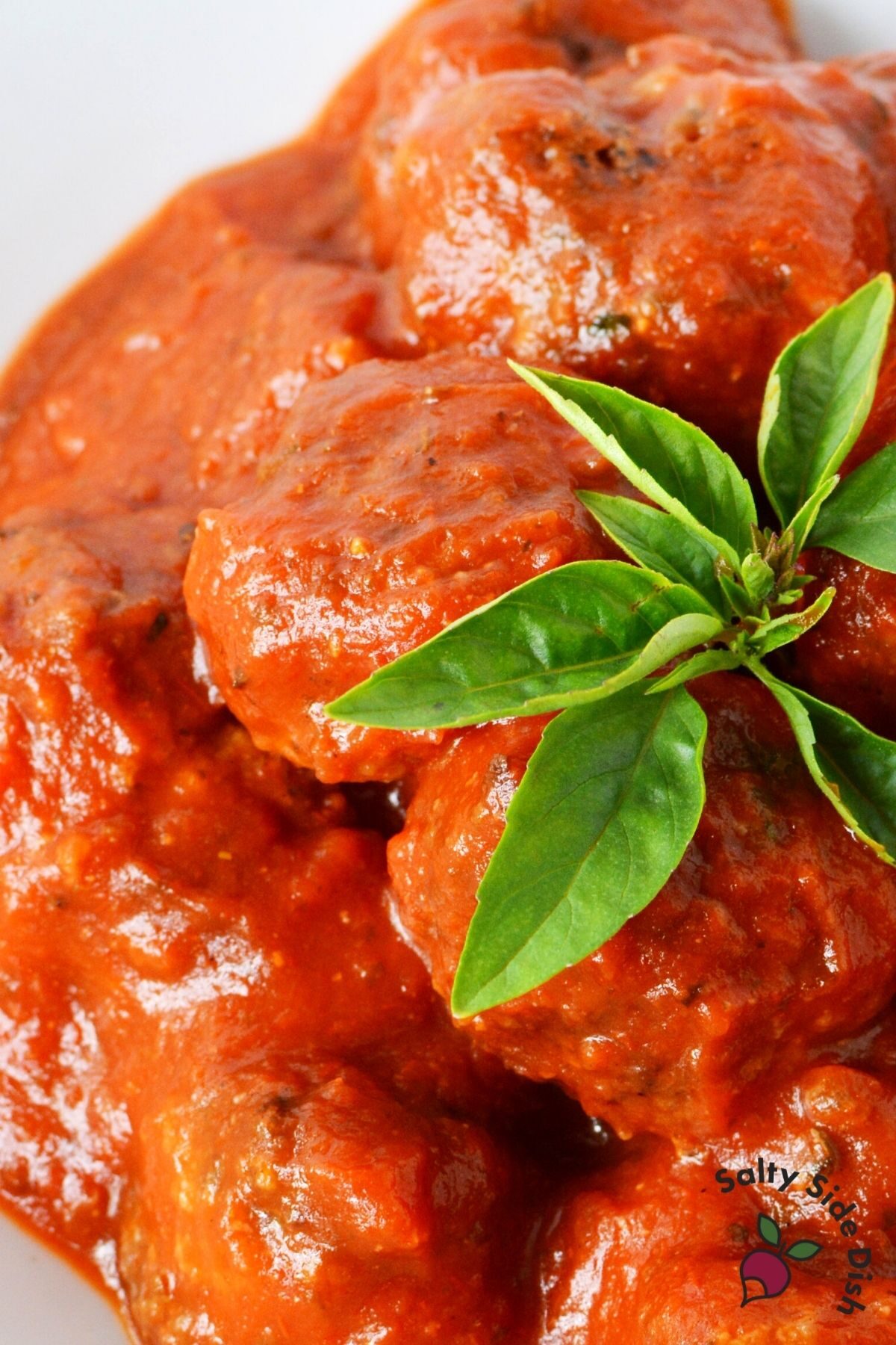 homemade meatballs with red sauce and dried herbs on top.