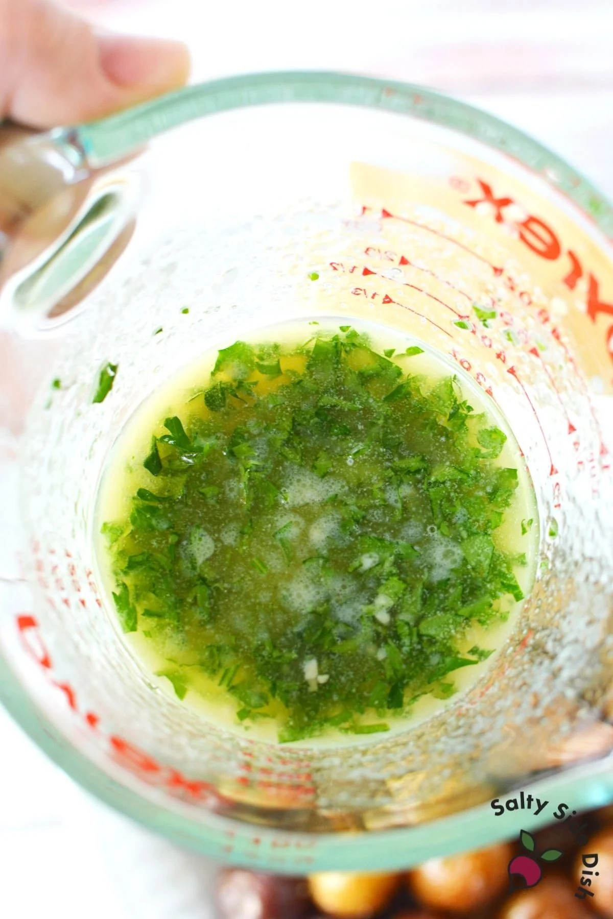 melted butter and fresh parsley in a measuring cup