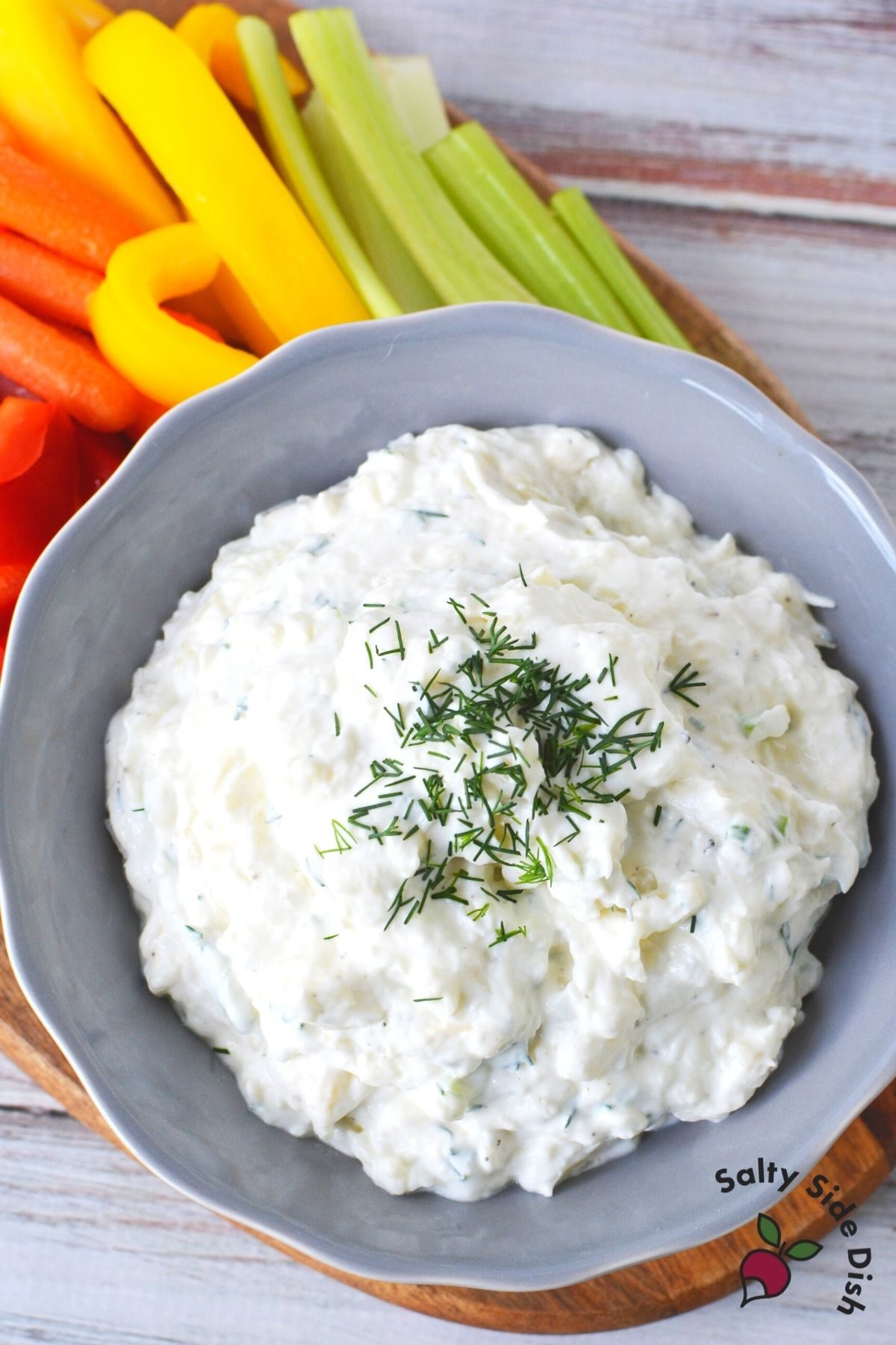bowl of garlic dip with red peppers and celery on side.