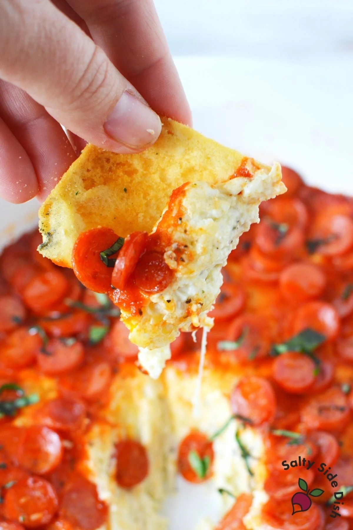 pita chip being dipped into and pulled out of pizza dip.
