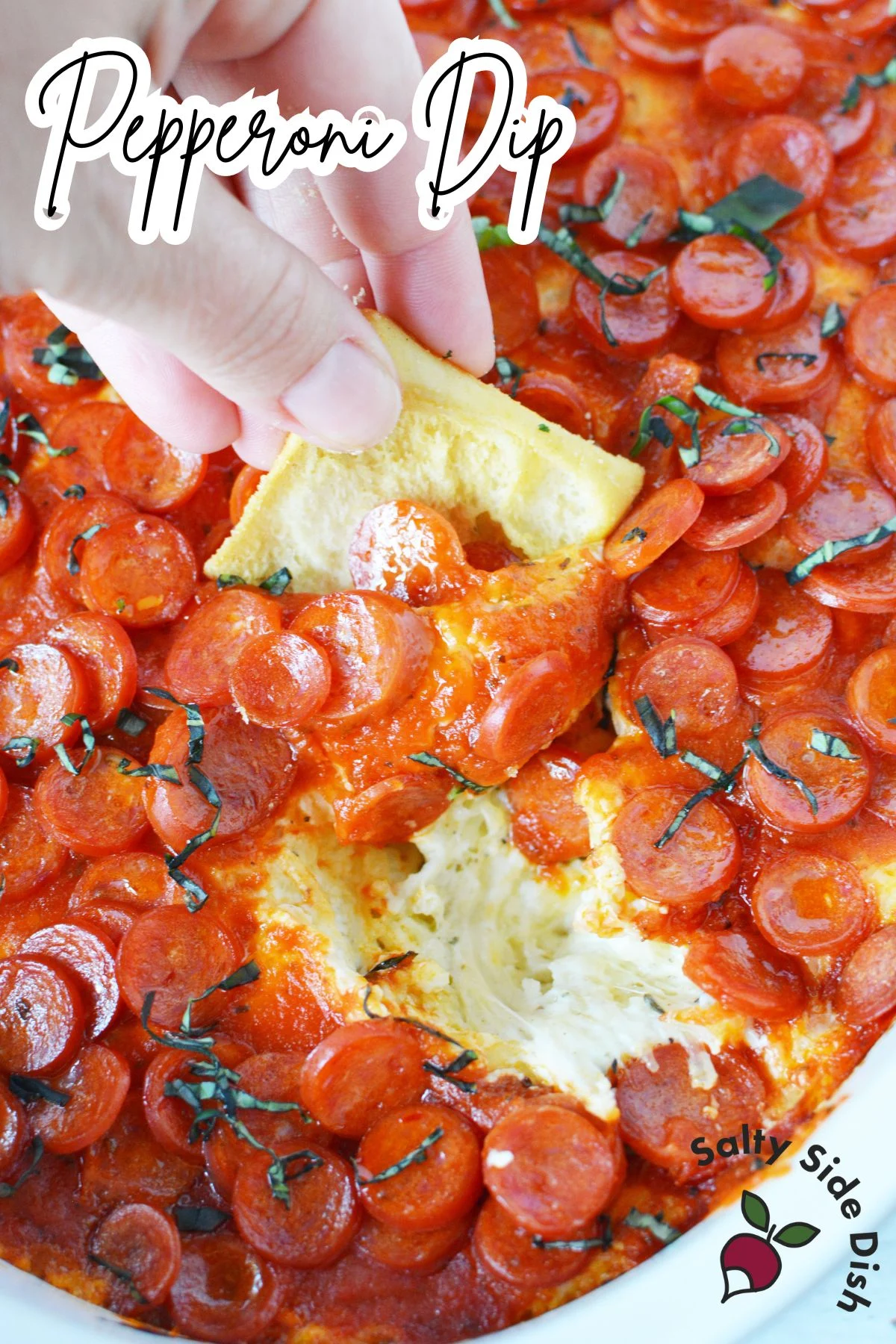 Pepperoni dip being dipped into the cheesy and mini pepperonis.