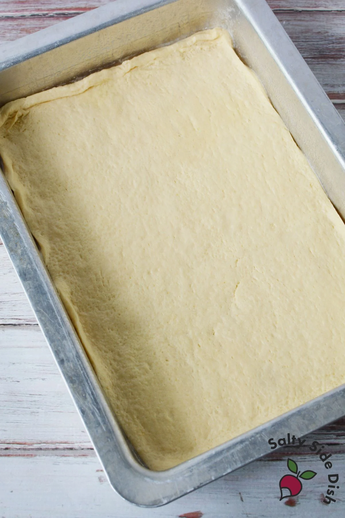 Pillsbury crescent roll sheet pressed into a baking pan for sopapilla cheesecake bars