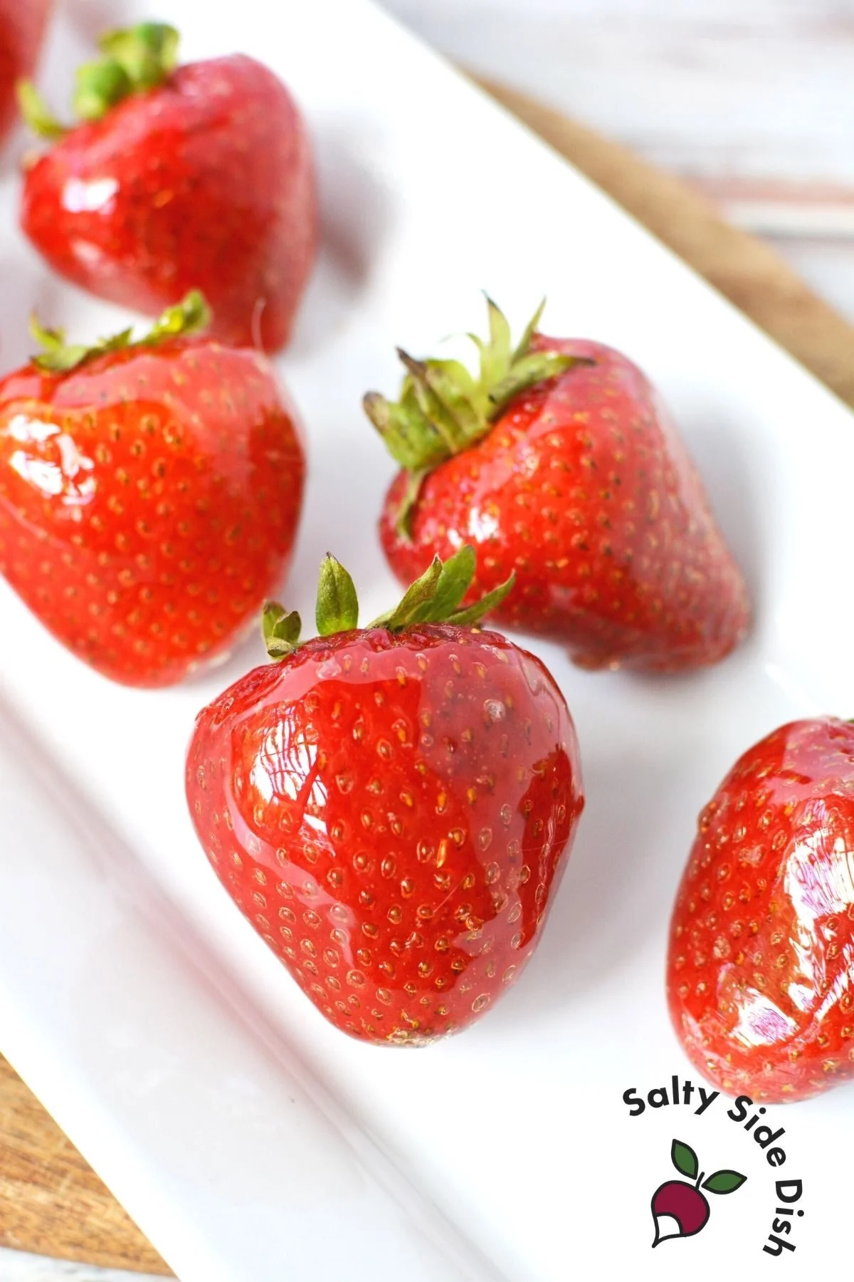 white plate with four tanghulu strawberries.