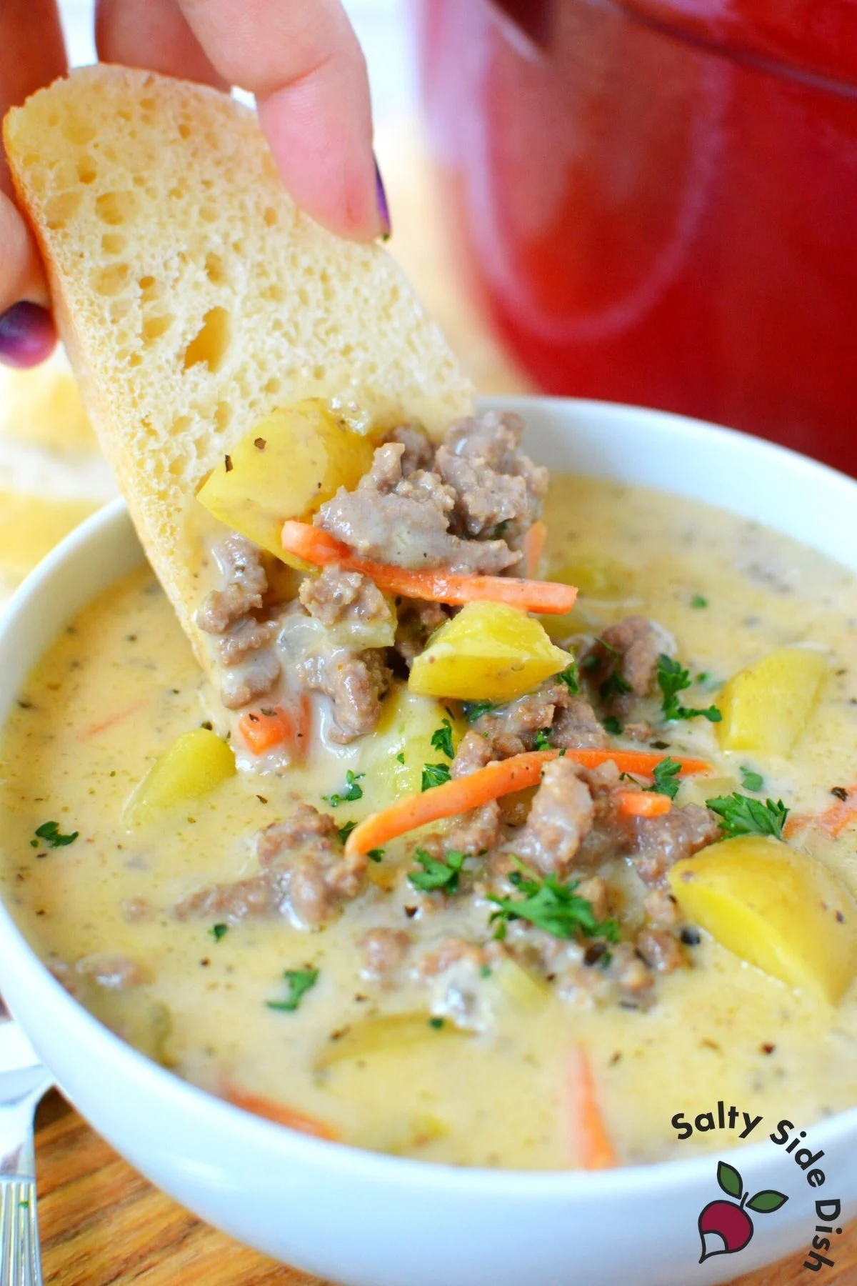 cheeseburger soup being dipped into with a piece of bread.