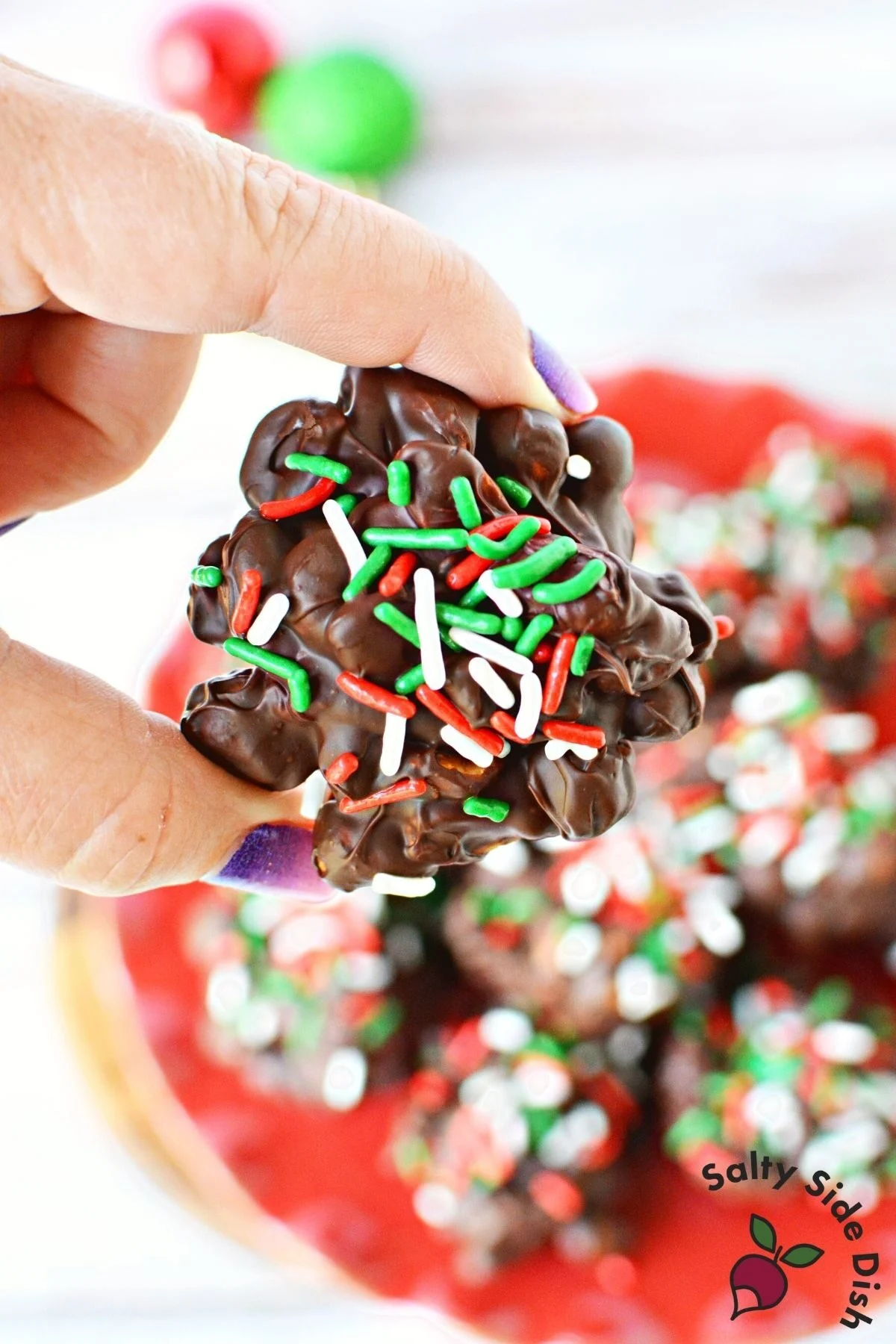 holding a chocolate peanut butter cluster.