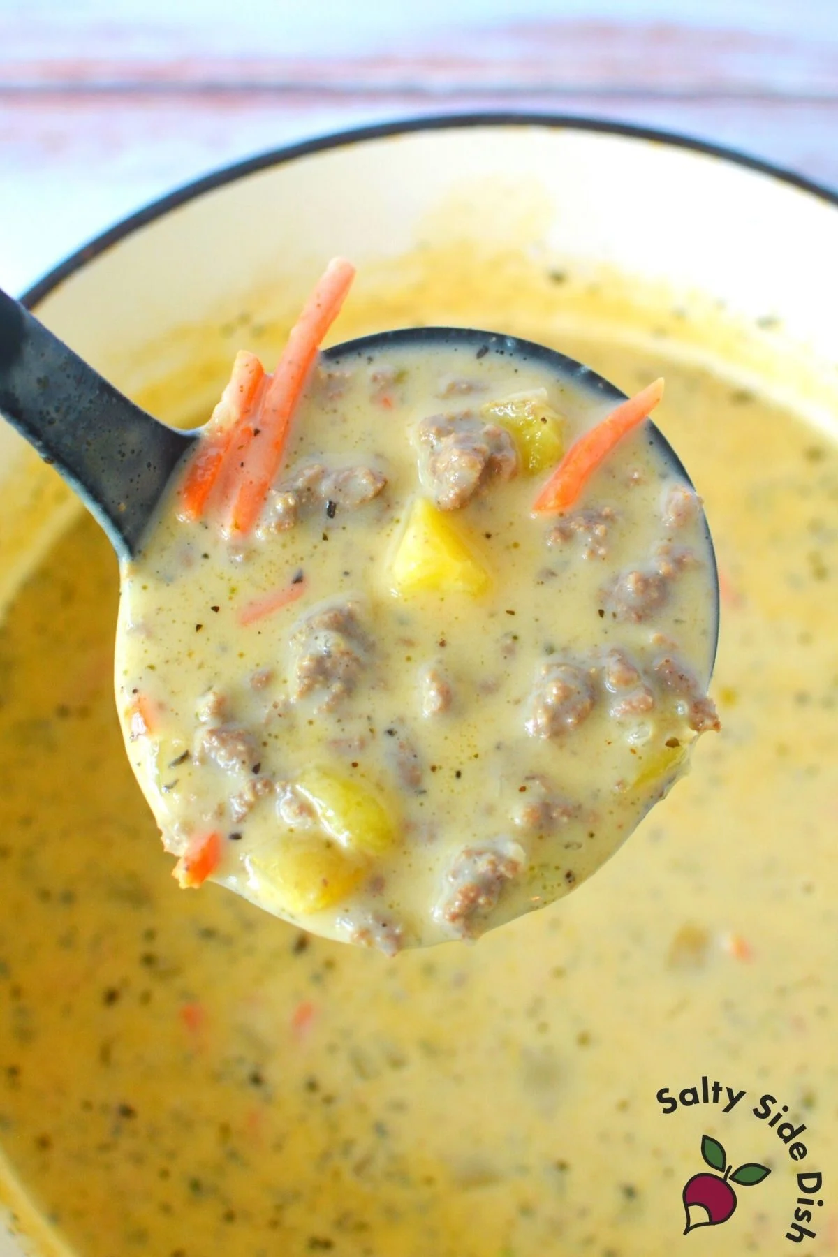 ladle dipping out a large scoop of creamy hamburger soup.