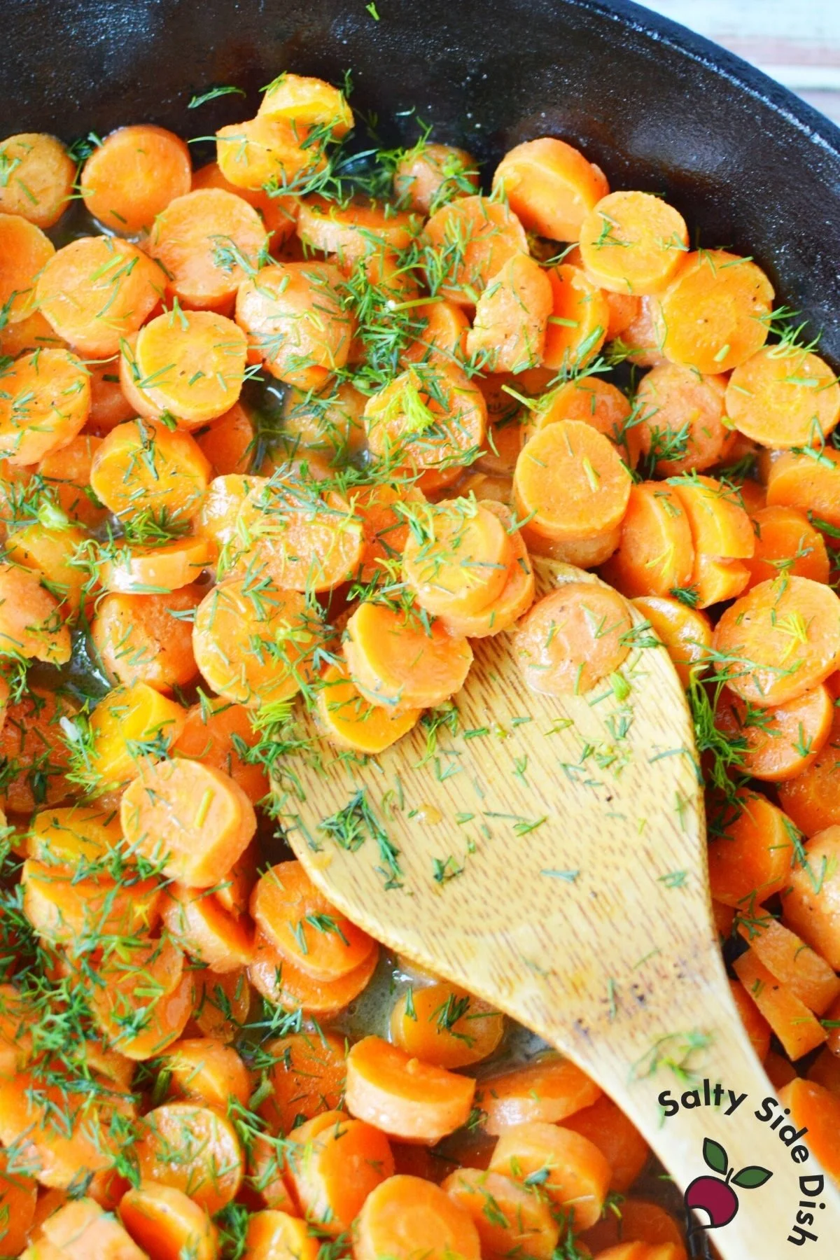 cast iron pan with dill and wooden spoon.