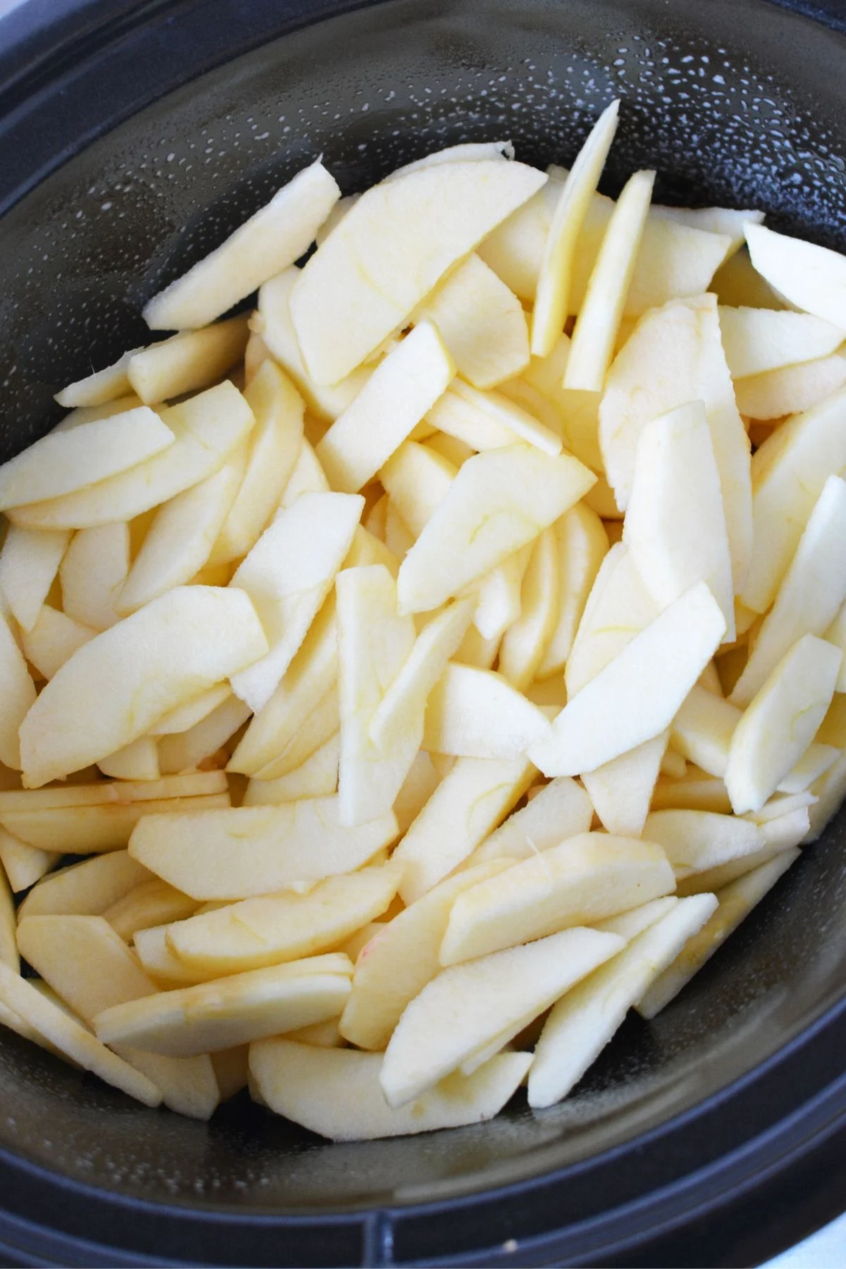Thin sliced apples in a crockpot.