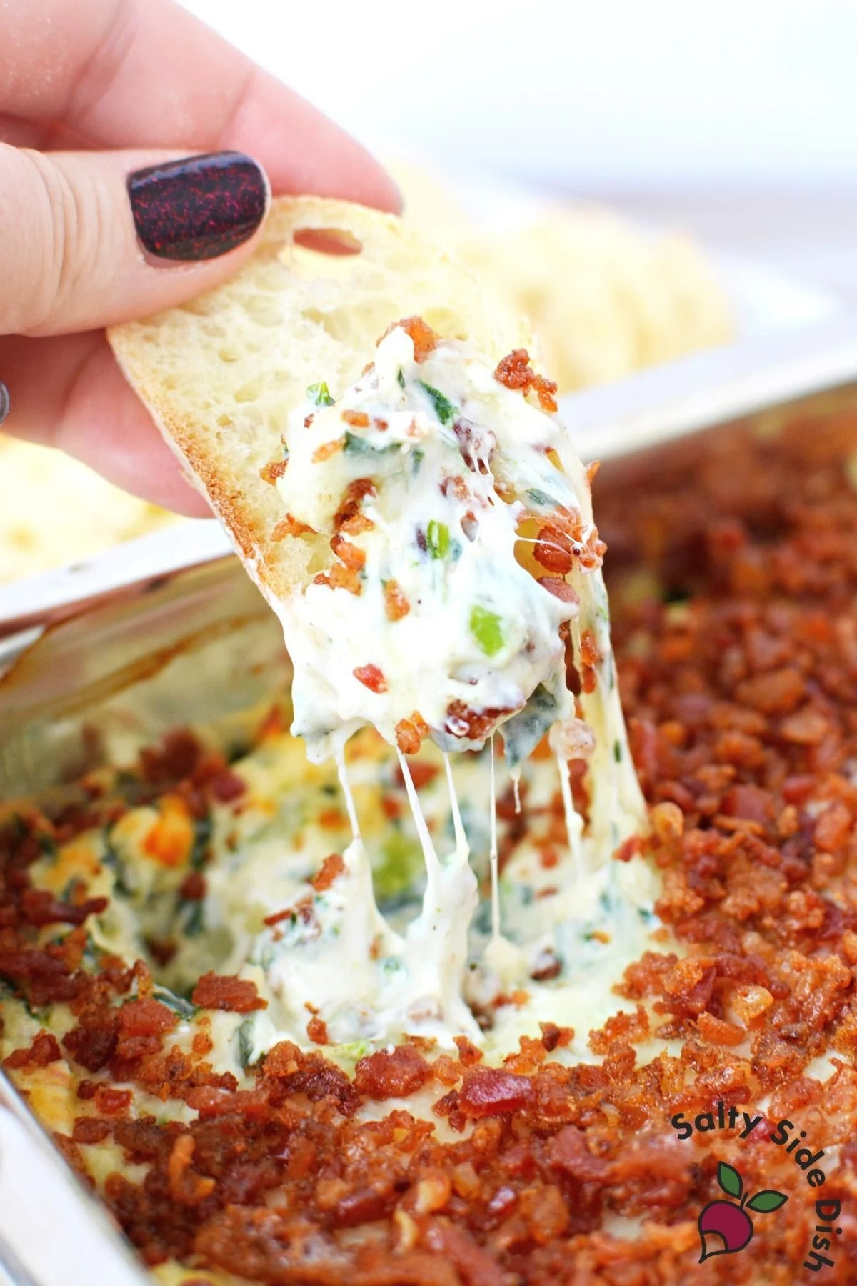 dipping bread into bacon spinach dip recipe.