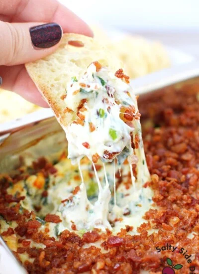 dipping bread into bacon spinach dip recipe.