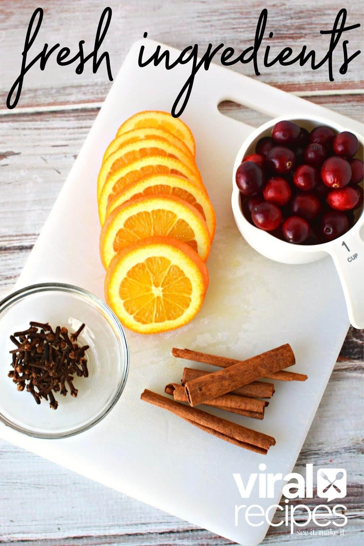 oranges, clove, cinnamon and cranberries on a platter.