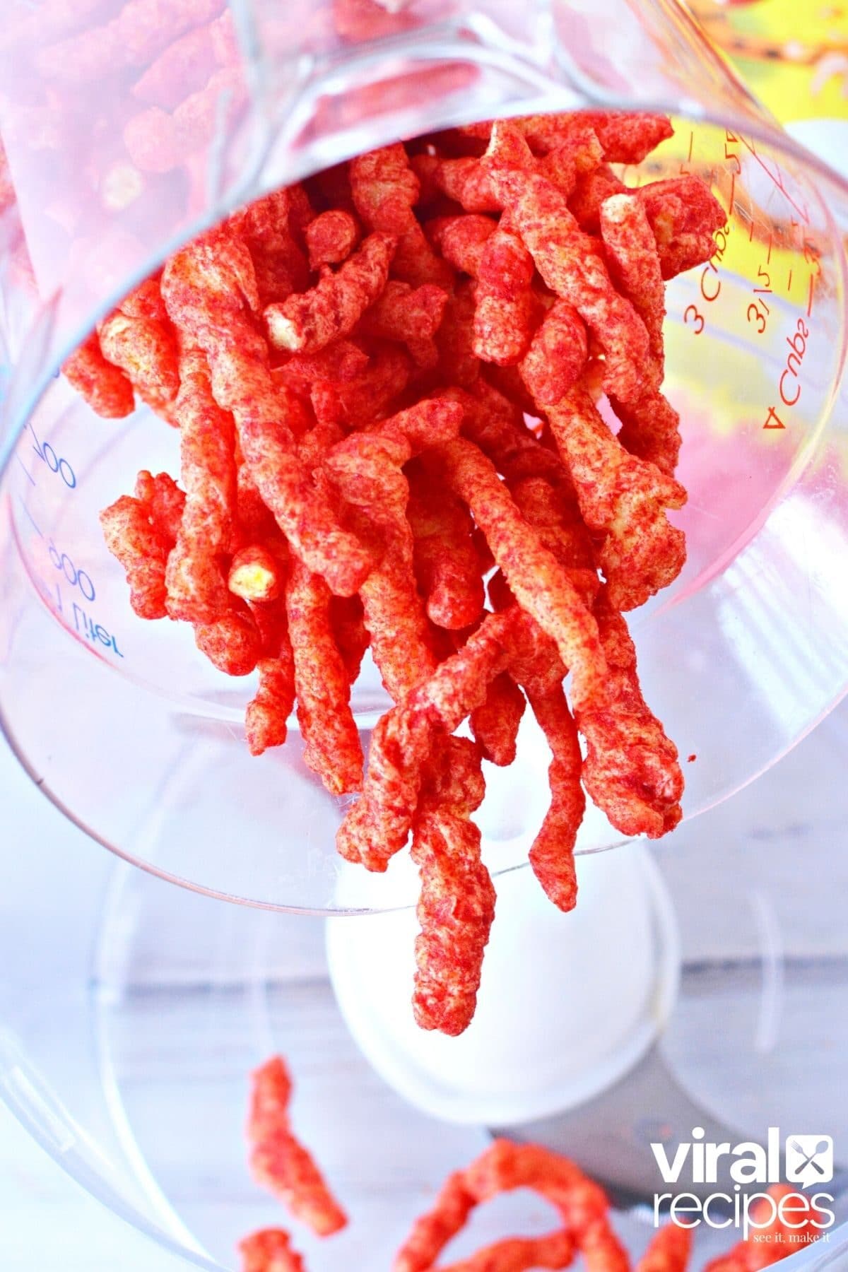 pouring cheetos into a food processor.