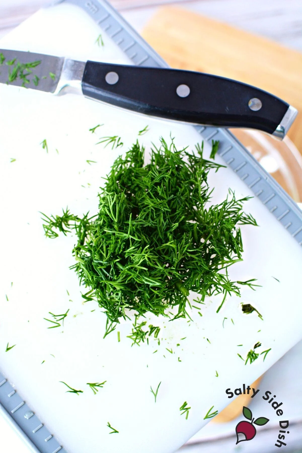 chopping dill weed on a cutting board.