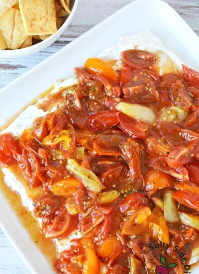 dip ready to serve on a plate with bowl of pita chips.